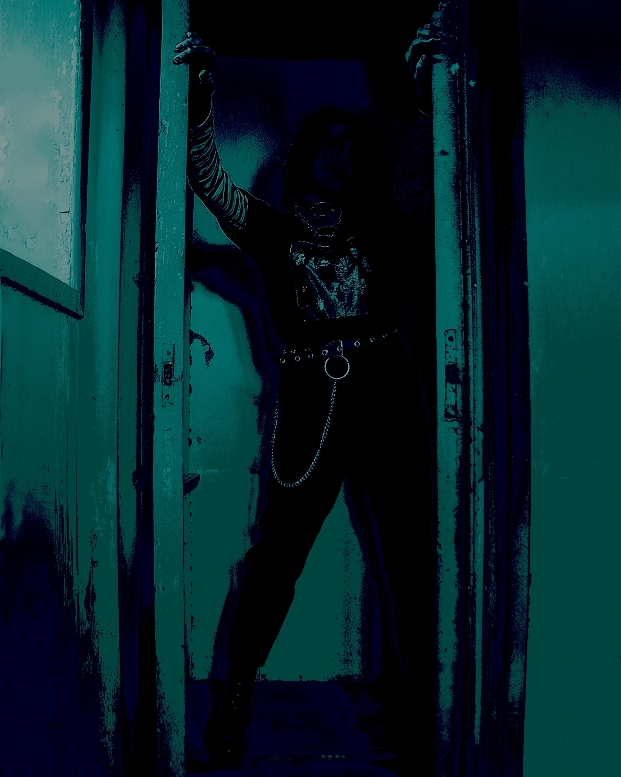 An individual exudes confidence, framed by a doorway, wearing striped sleeves and dark pants adorned with chains, encapsulating a metalhead's expressive wardrobe.