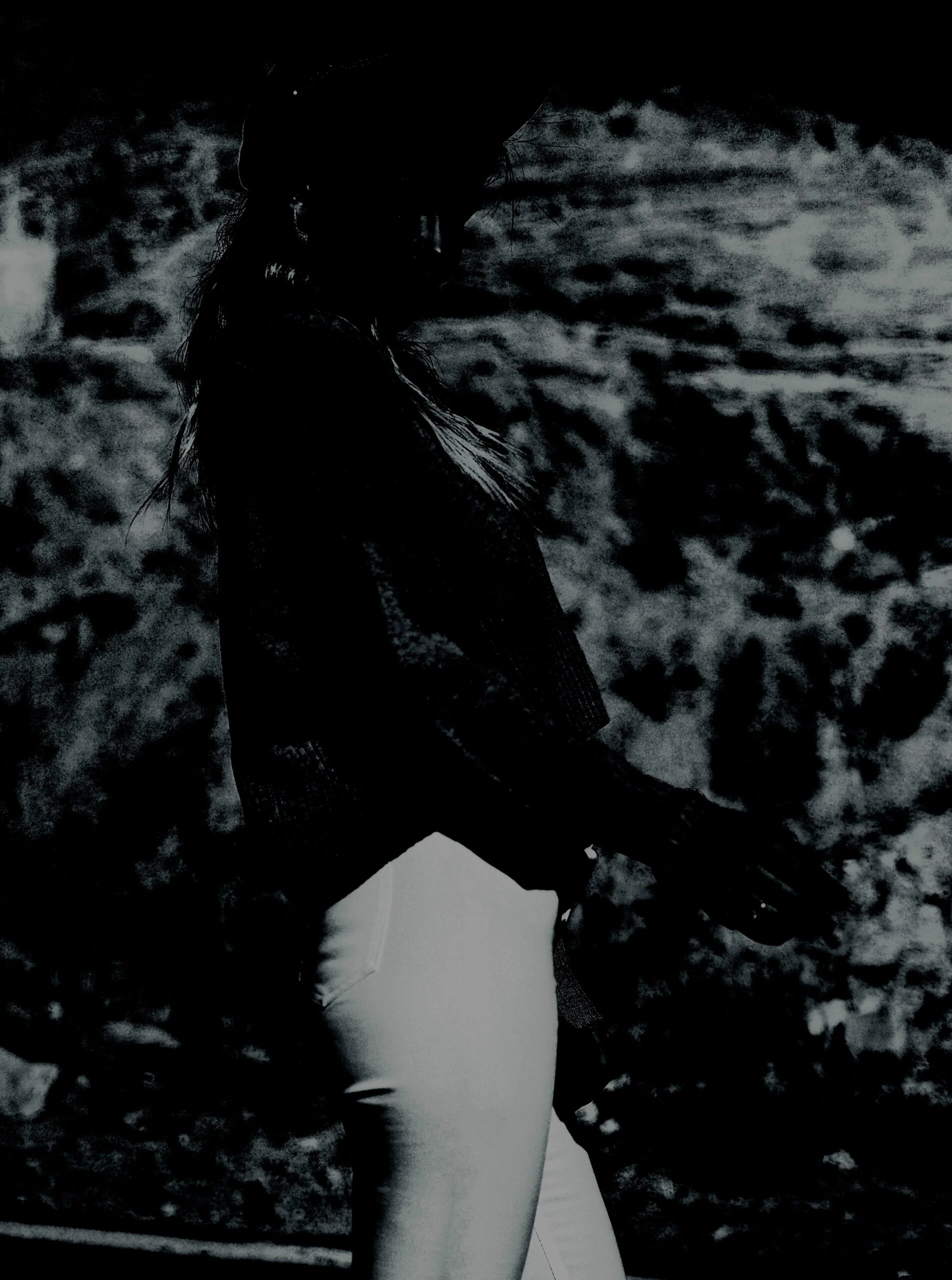 A silhouette set against a textured background, wearing flared light pants, offering a contrast to the dark, moody atmosphere typical of gothic fashion.