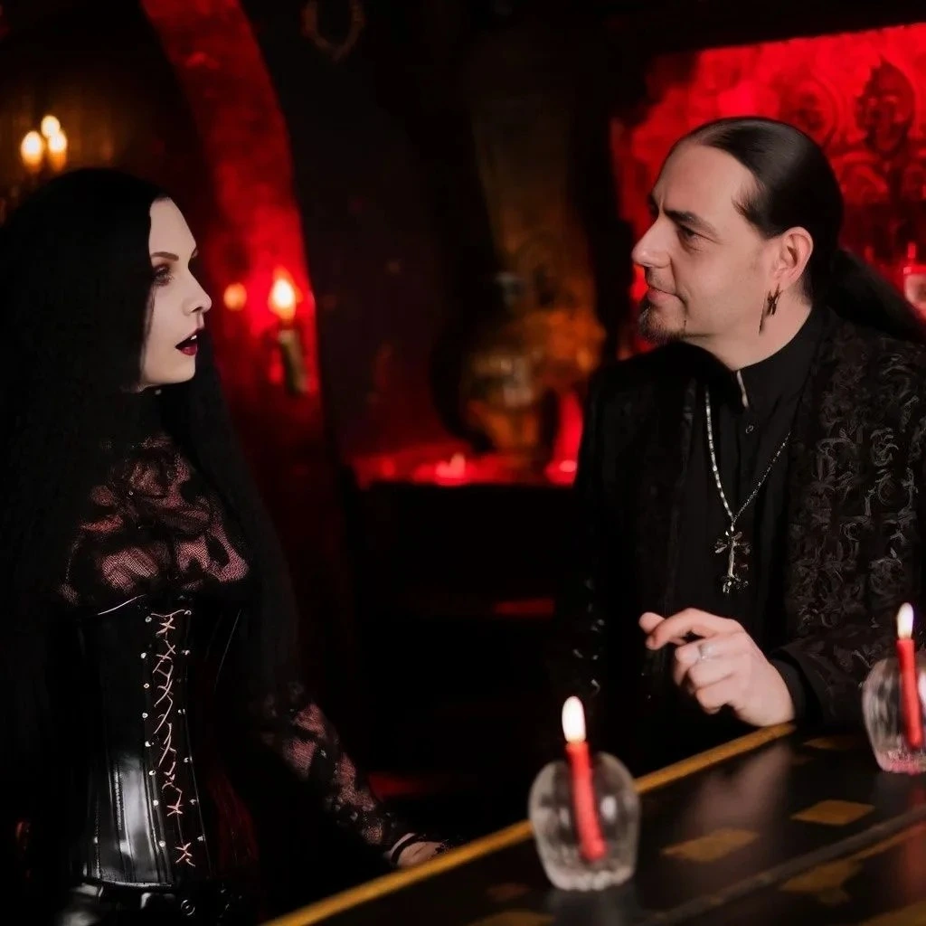 Goth couple at a bar, with the man in a velvet blazer and the woman in a corset, both engaging in a serious discussion.