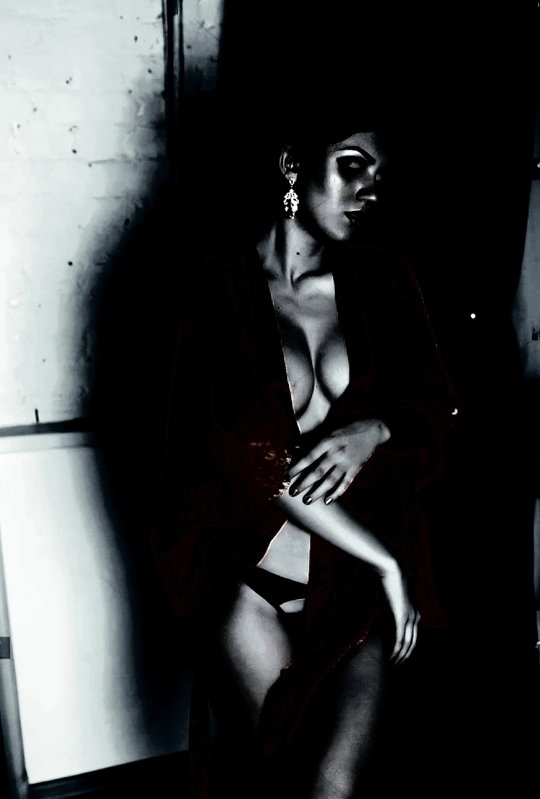 Figure in a dark, textured setting conveying gender fluidity with an intense, contemplative gaze.