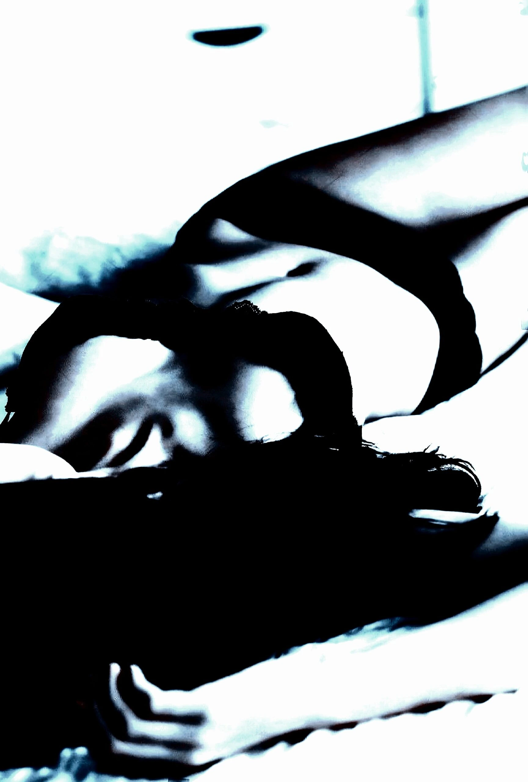 Contorted figure in repose, creating a striking visual narrative of gender fluidity in shadow play.