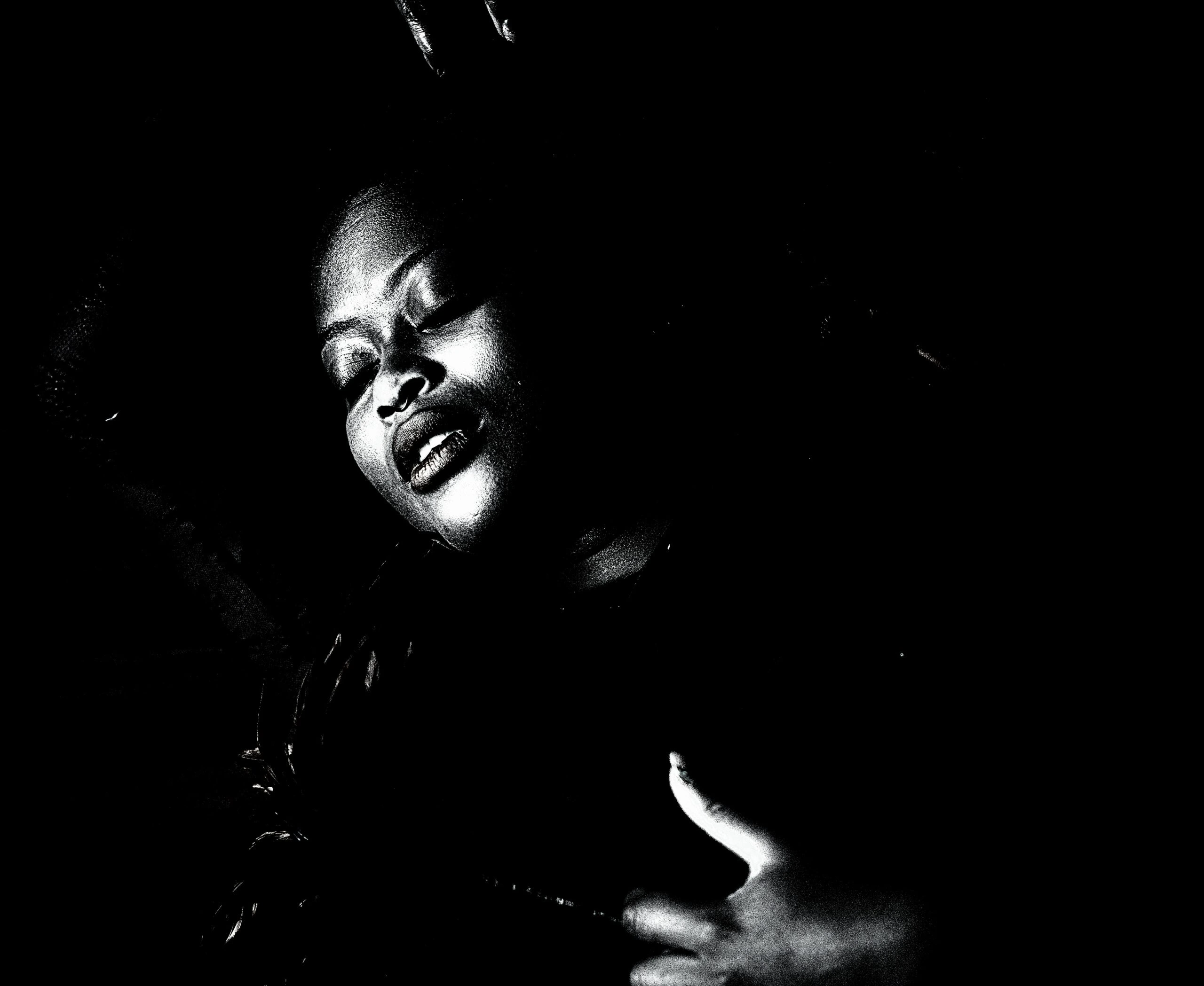 An artistic monochrome portrayal of a person's face in partial shadow, with an expression of serene submission, reflecting the intensity of the moment.