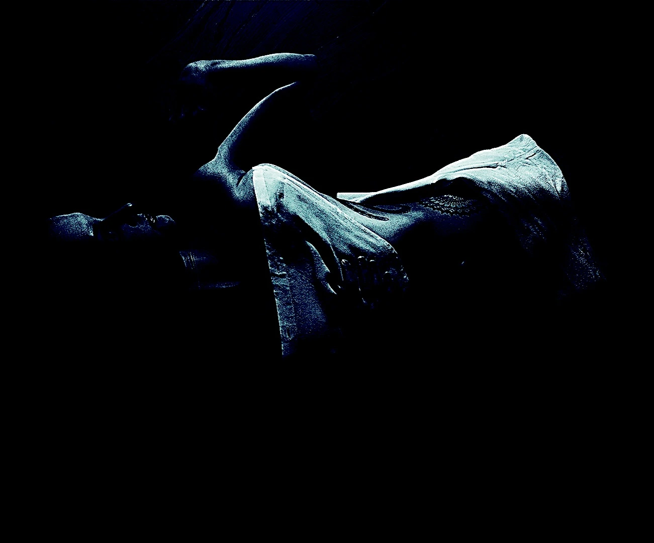 Abstract monochrome image focused on a bound individual's wrists, highlighting the details of the restraint device against a stark black background.