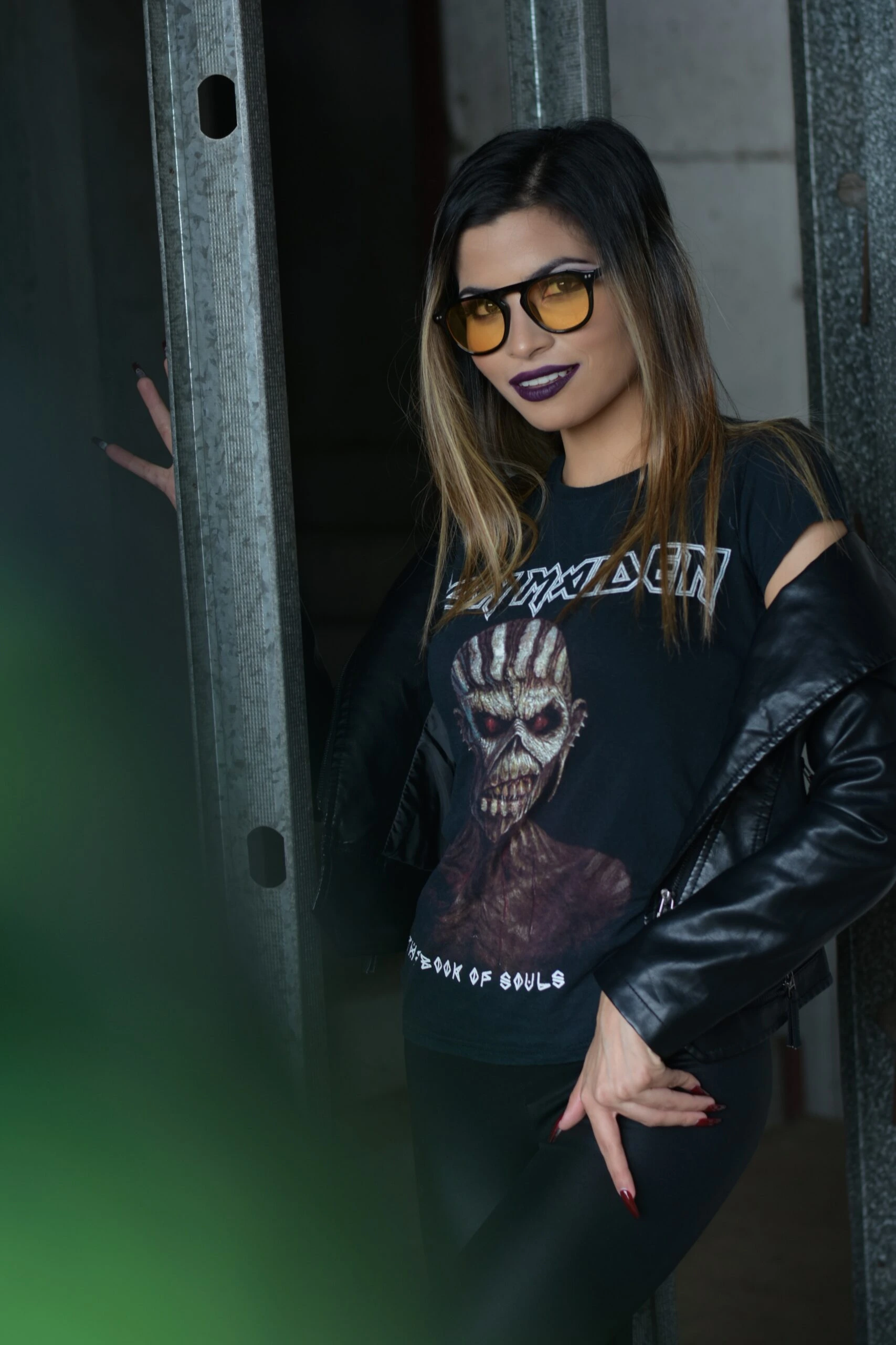 Confident woman showcasing Victorian grandeur meets modern edge in Iron Maiden band tee and black leather jacket.