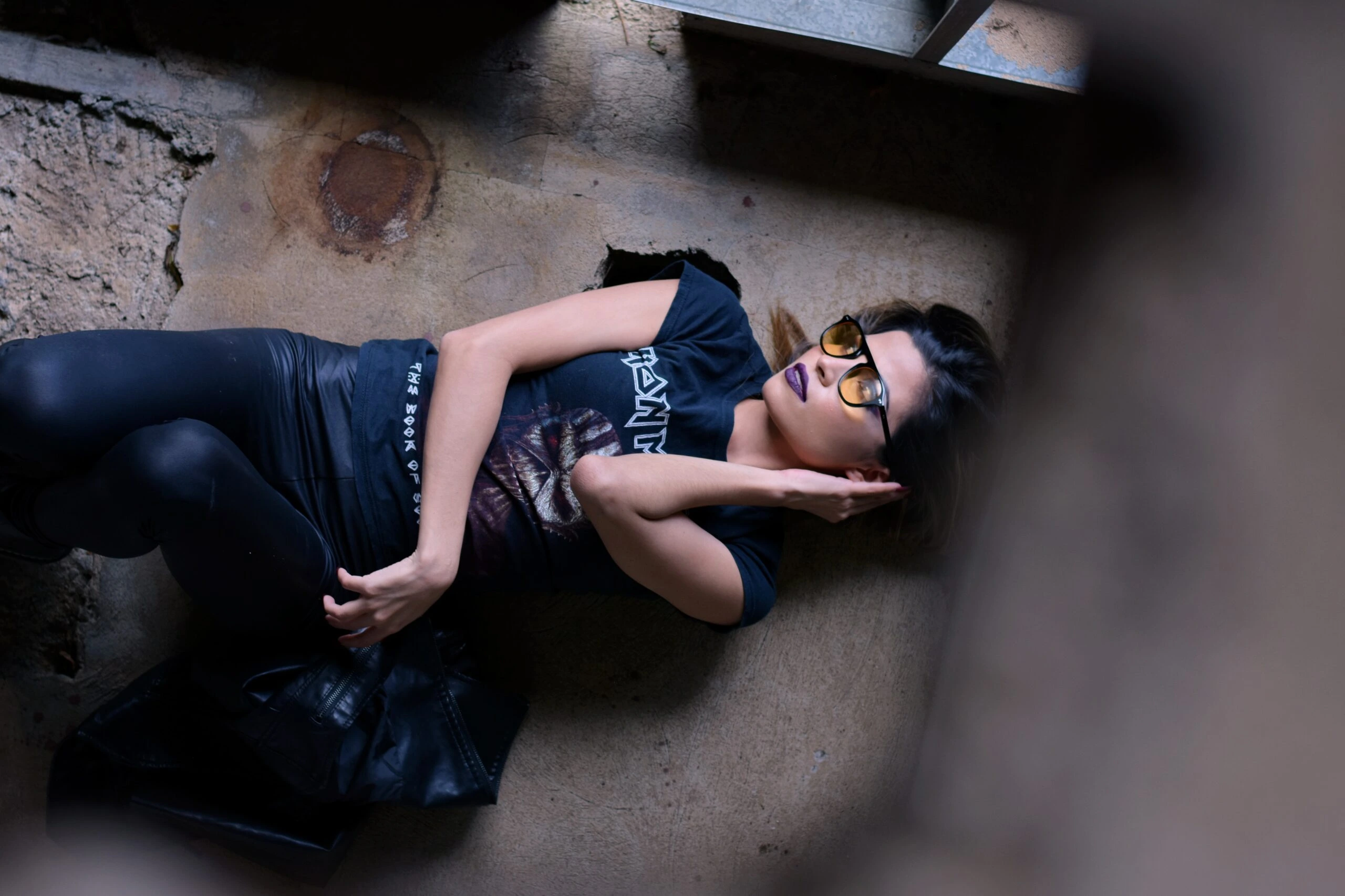 Woman in a relaxed pose exuding Victorian grandeur meets modern edge with Iron Maiden tee and leather leggings.