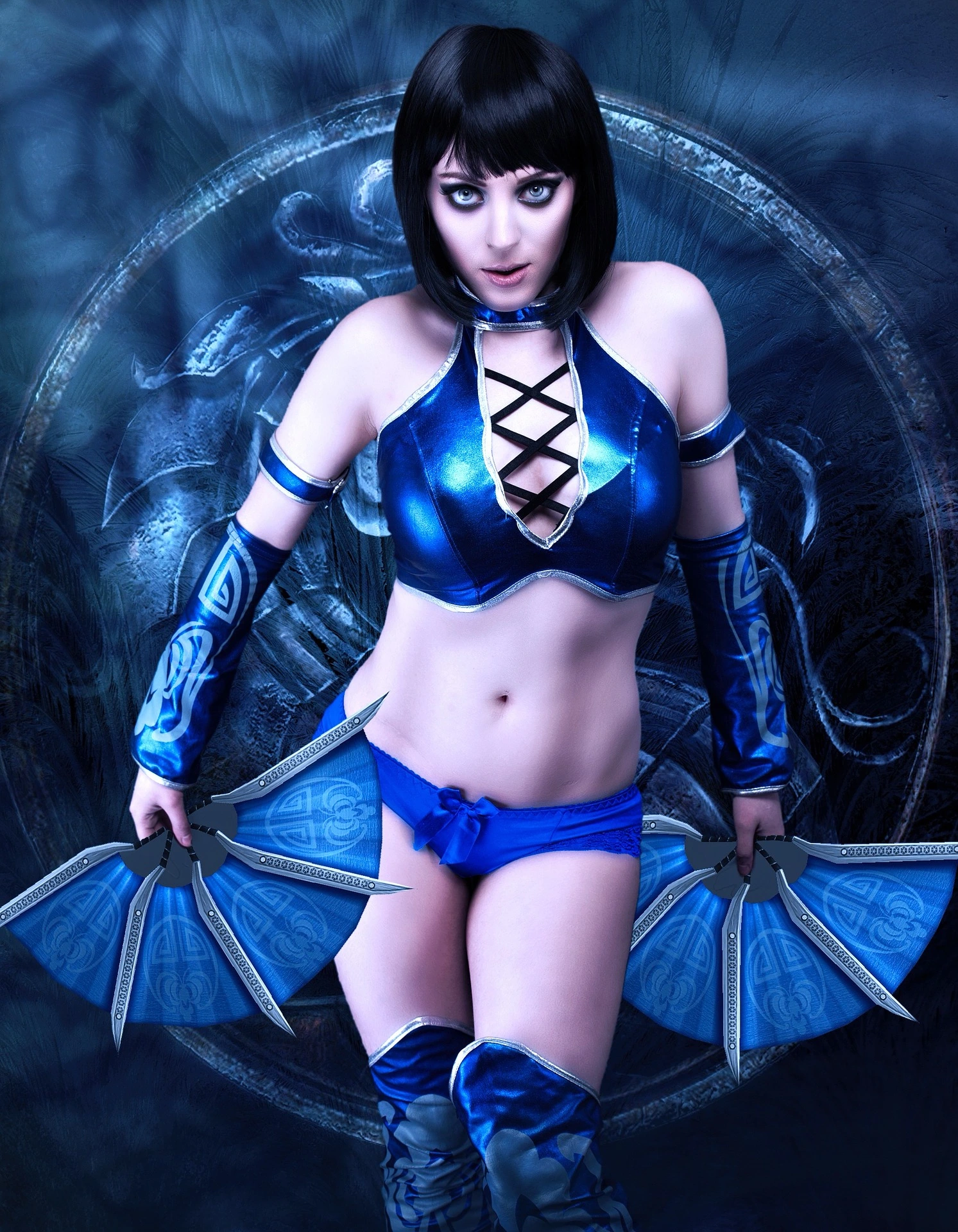 Cosplayer in a blue warrior-inspired outfit with intricate arm tattoos and fan blades.