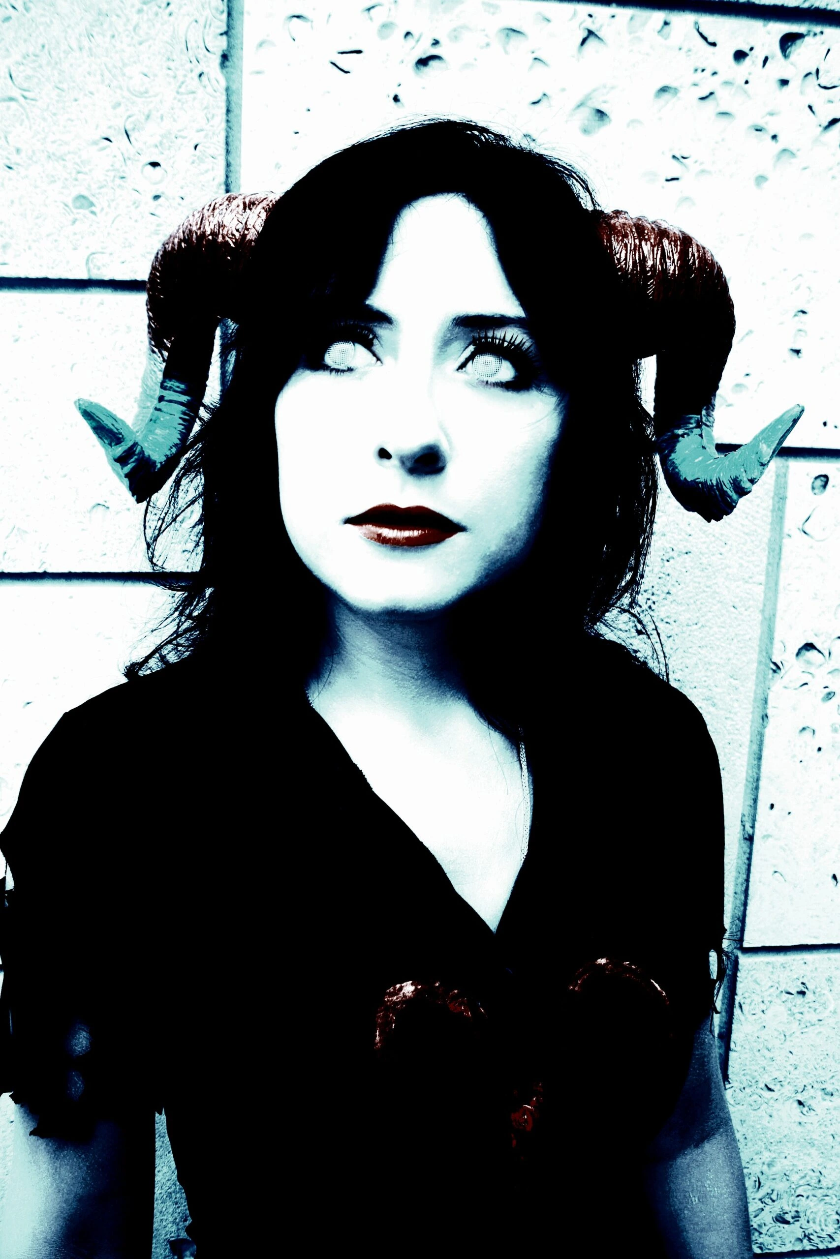 Gothic style woman with an ethereal pose, highlighted by dark attire and white hair, against a blue-tinted urban backdrop.