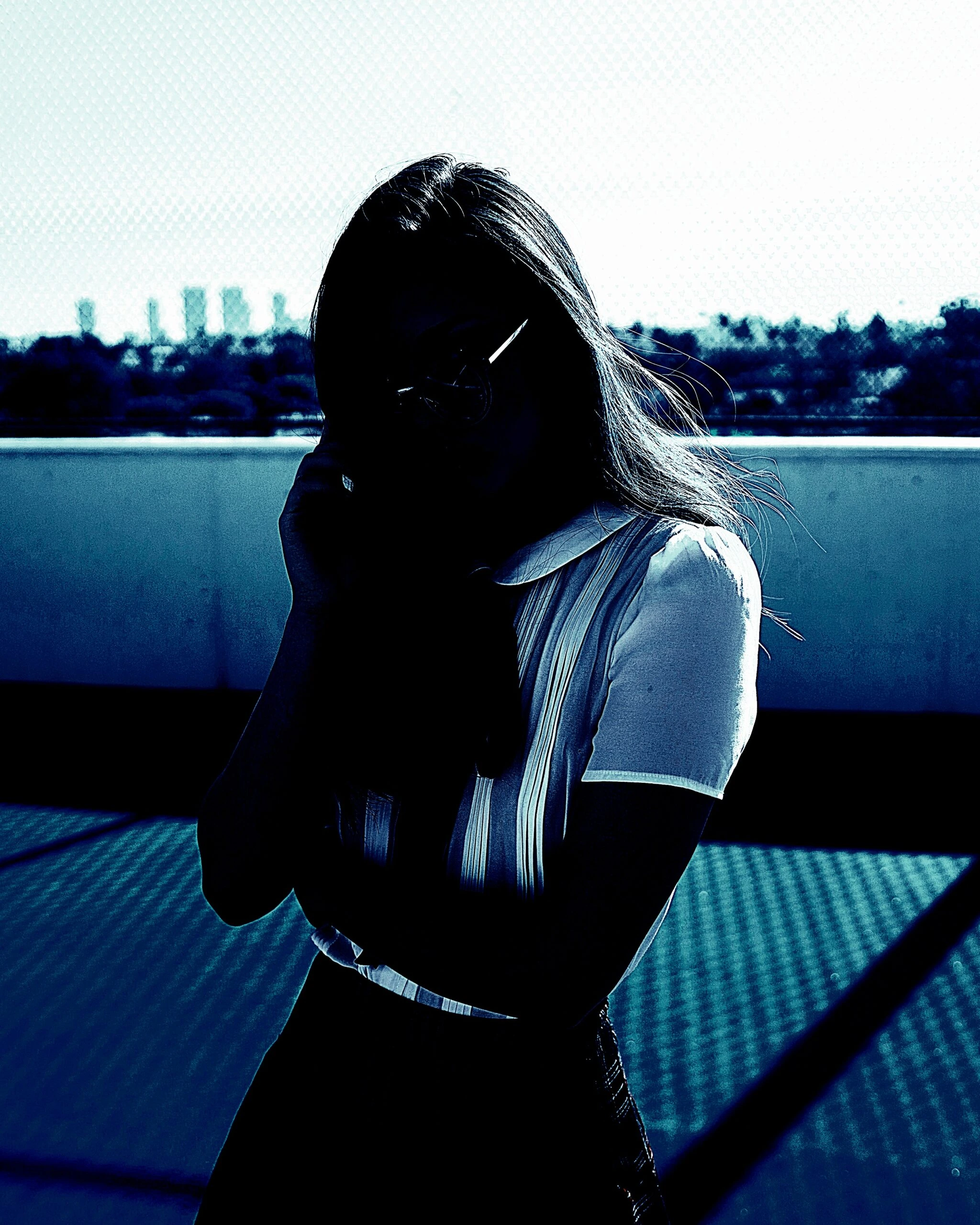 Goth woman with intense gaze and dark makeup, featuring heavy blue tones and high contrast, exuding a mysterious aura.