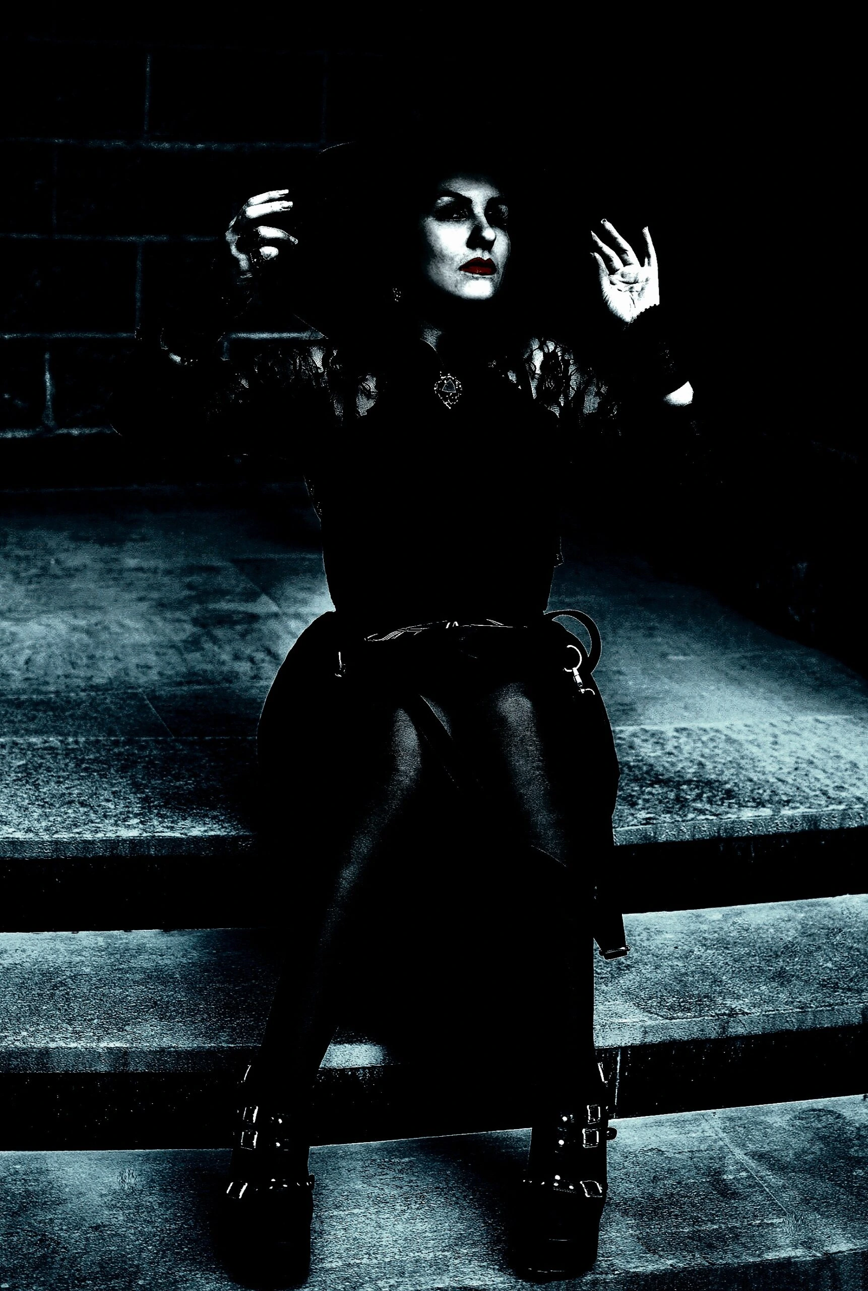 A gothic figure with a dramatic pose seated on stairs, cloaked in shadow with striking contrast, evoking a sense of dark elegance.
