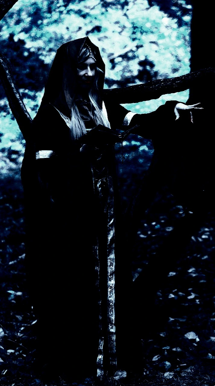 Woman seated on metal stairs in a striking gothic outfit with tall boots and a jacket, holding a fan, set against a blue-toned backdrop.