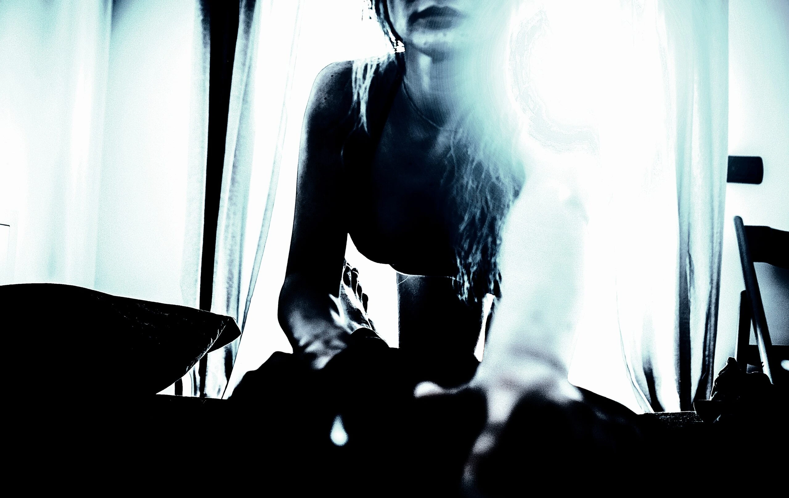 A stylized, high-contrast image depicting a silhouette that evokes the future of BDSM, with indistinct features and an ethereal glow, set against a backdrop of diaphanous curtains and minimalist interior.