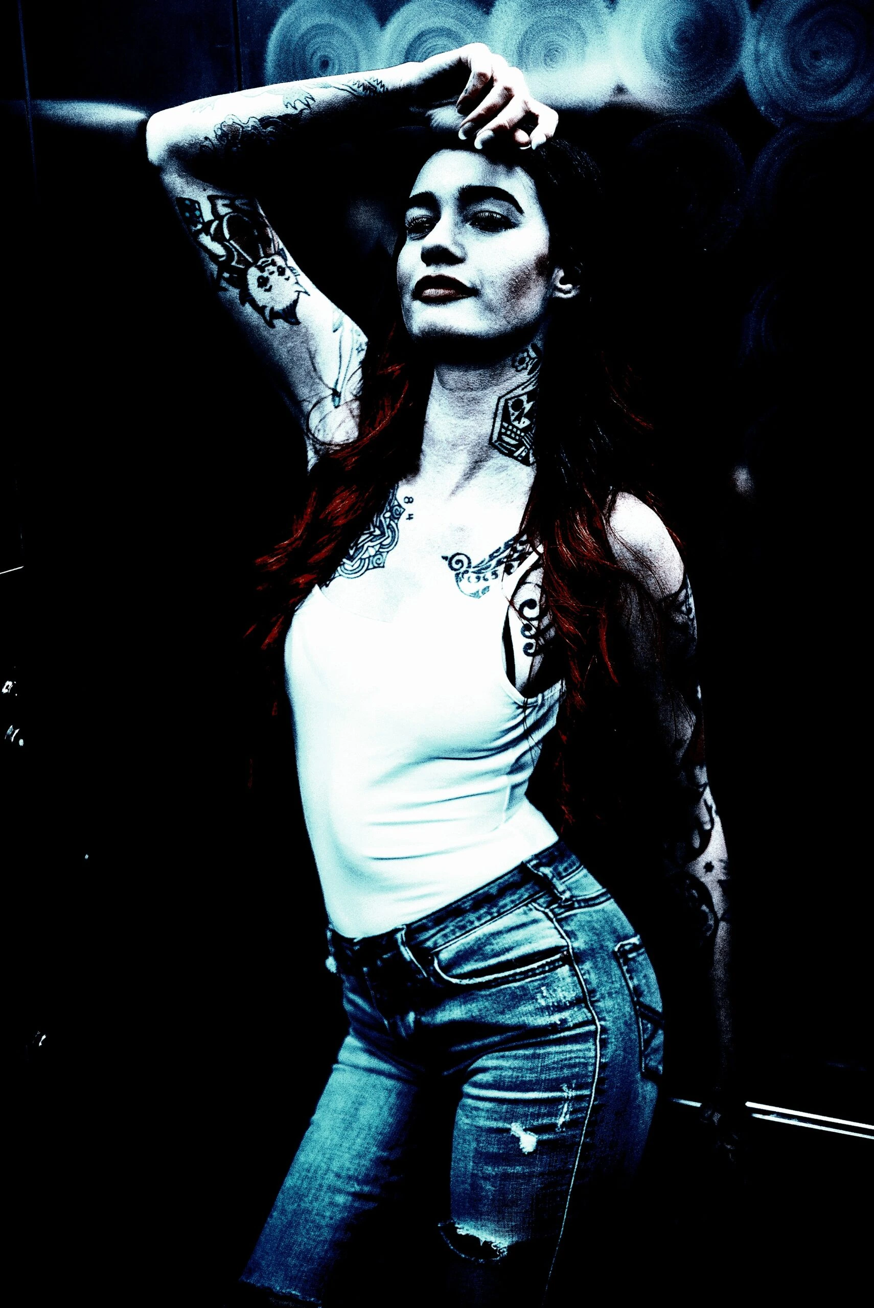 A person with red hair and intricate tattoos, including a heart and filigree designs on the arms, exuding a confident rock vibe against a psychedelic background.