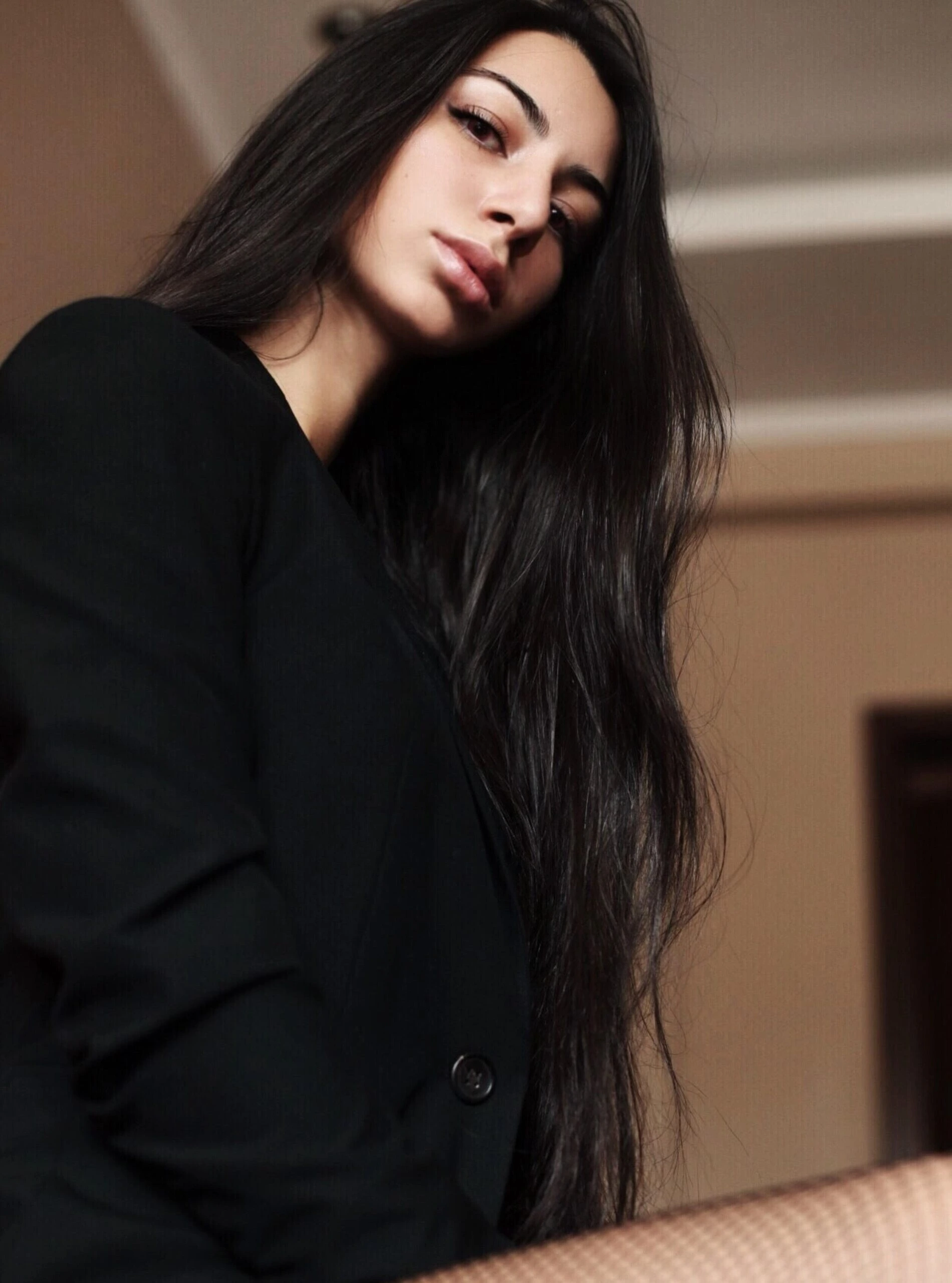 Woman with long black hair and intense gaze wearing a black suit, perfect for a Hot Vampire Halloween Costume.