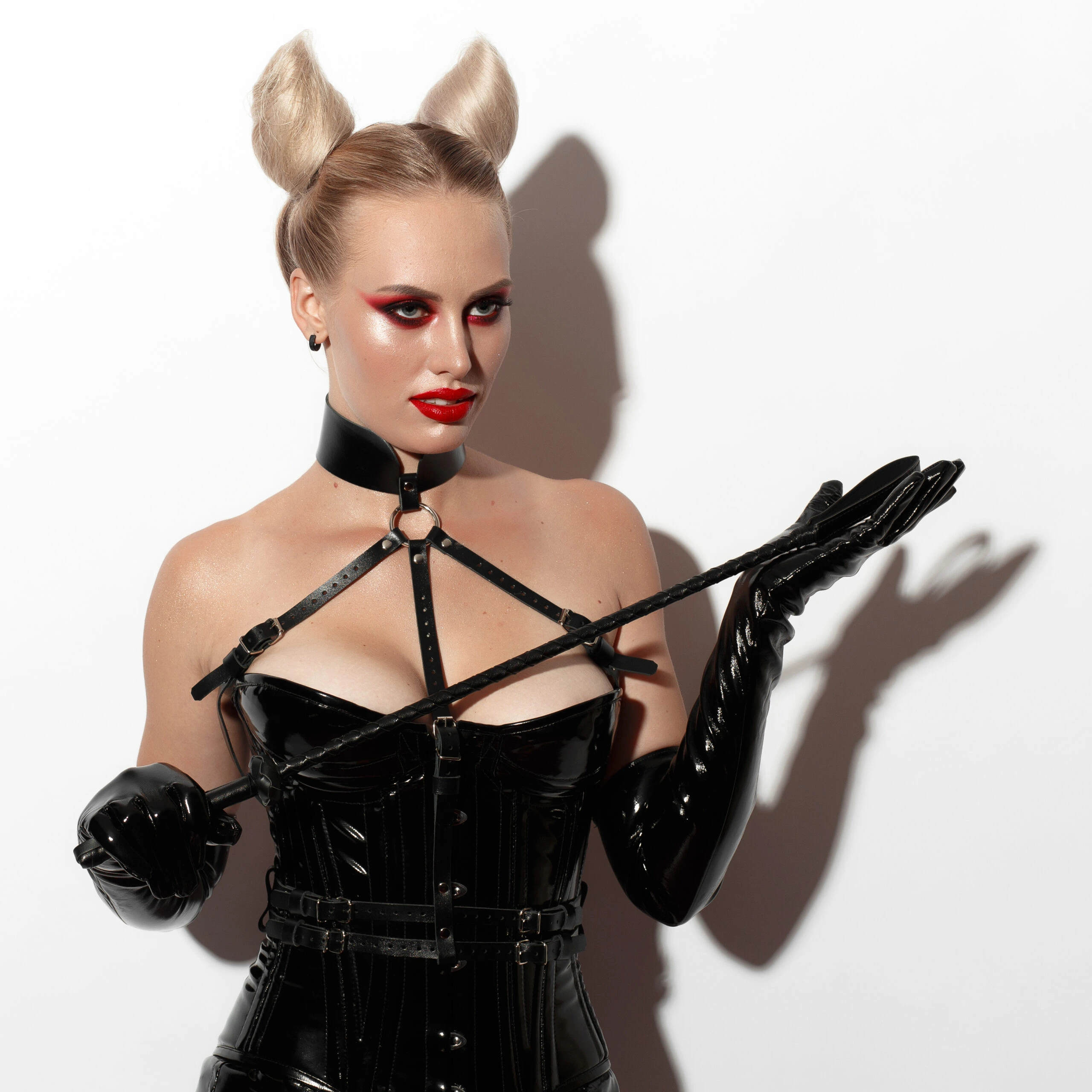 Woman in a black leather corset with a choker collar, holding a whip, embodying the dominatrix style. Ultimate Guide to Dominatrix Fashion.