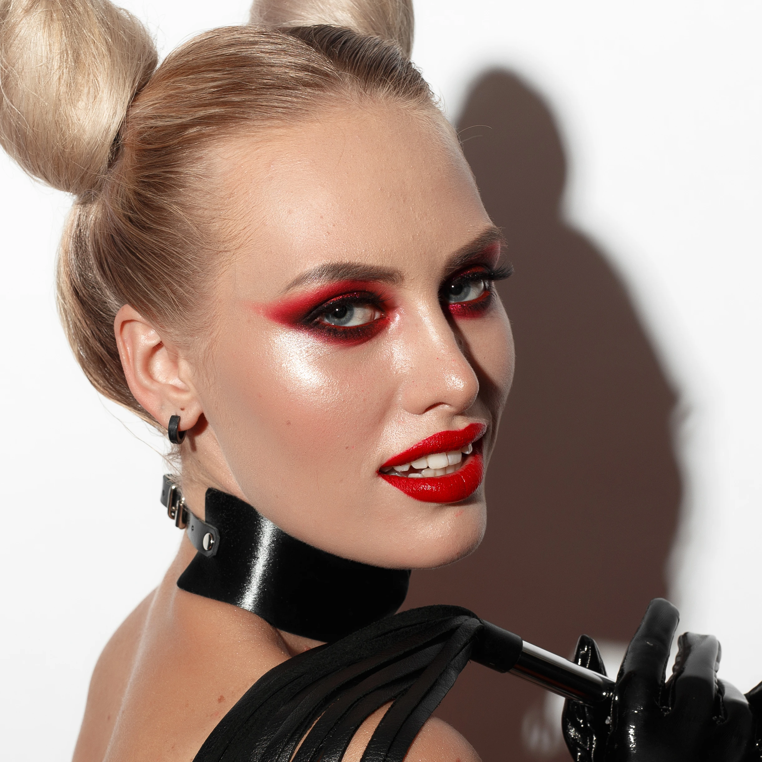 Close-up of a woman with bold red eye makeup and a black choker collar, representing dominatrix fashion. Ultimate Guide to Dominatrix Fashion.