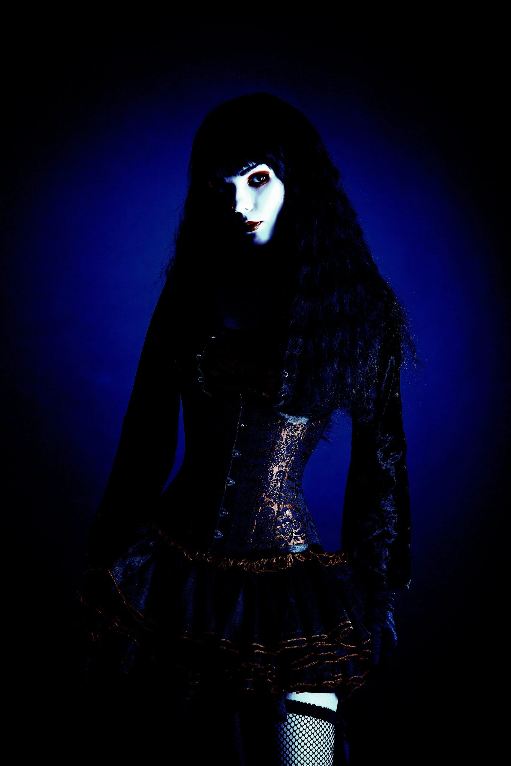 Gothic fashion model in a dark ensemble with a wide-brimmed hat, showcasing a blend of Victorian and modern styles.