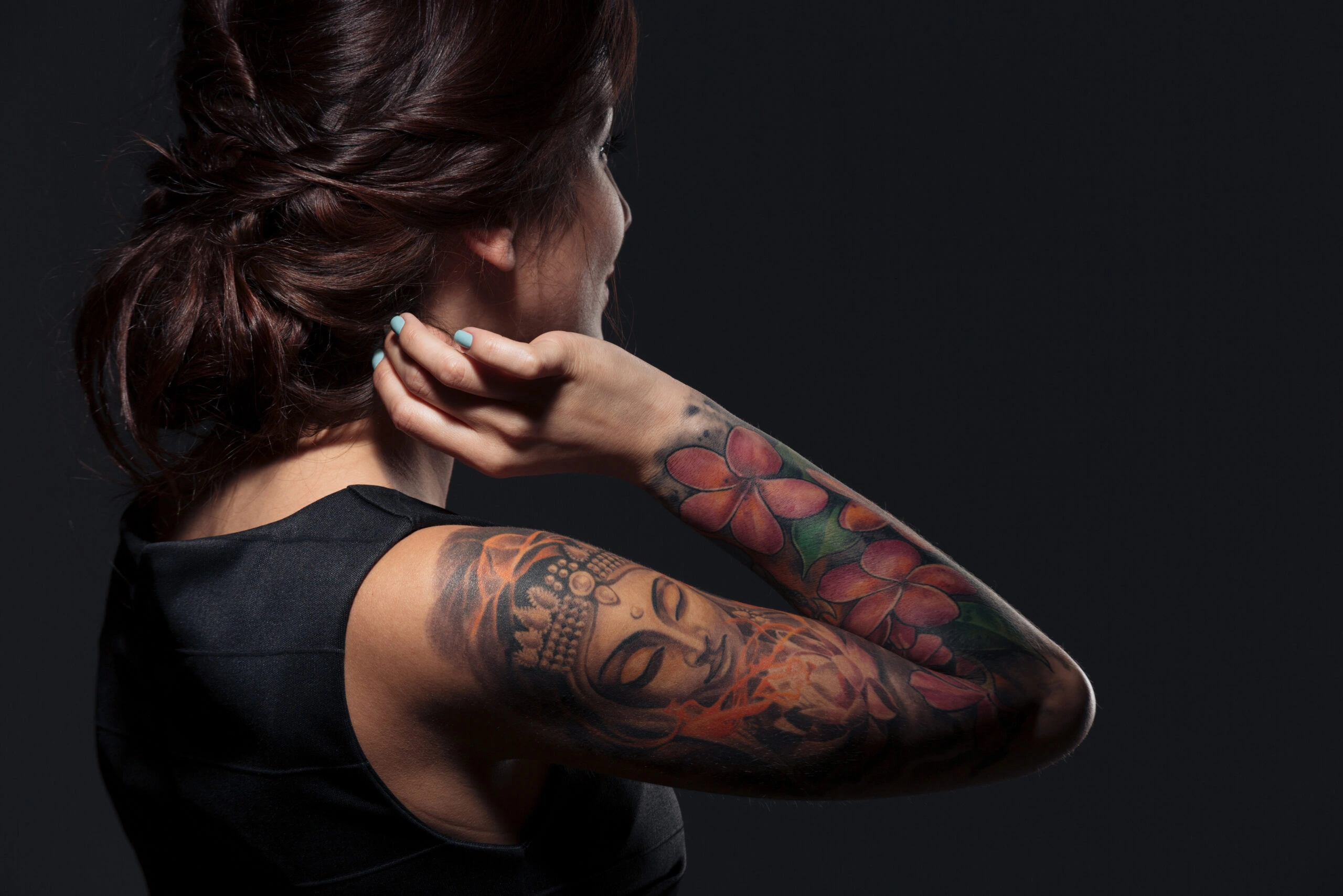 Back view of a woman with a detailed Buddha tattoo, reflecting spiritual themes in Tattoos in the Metal Subculture.