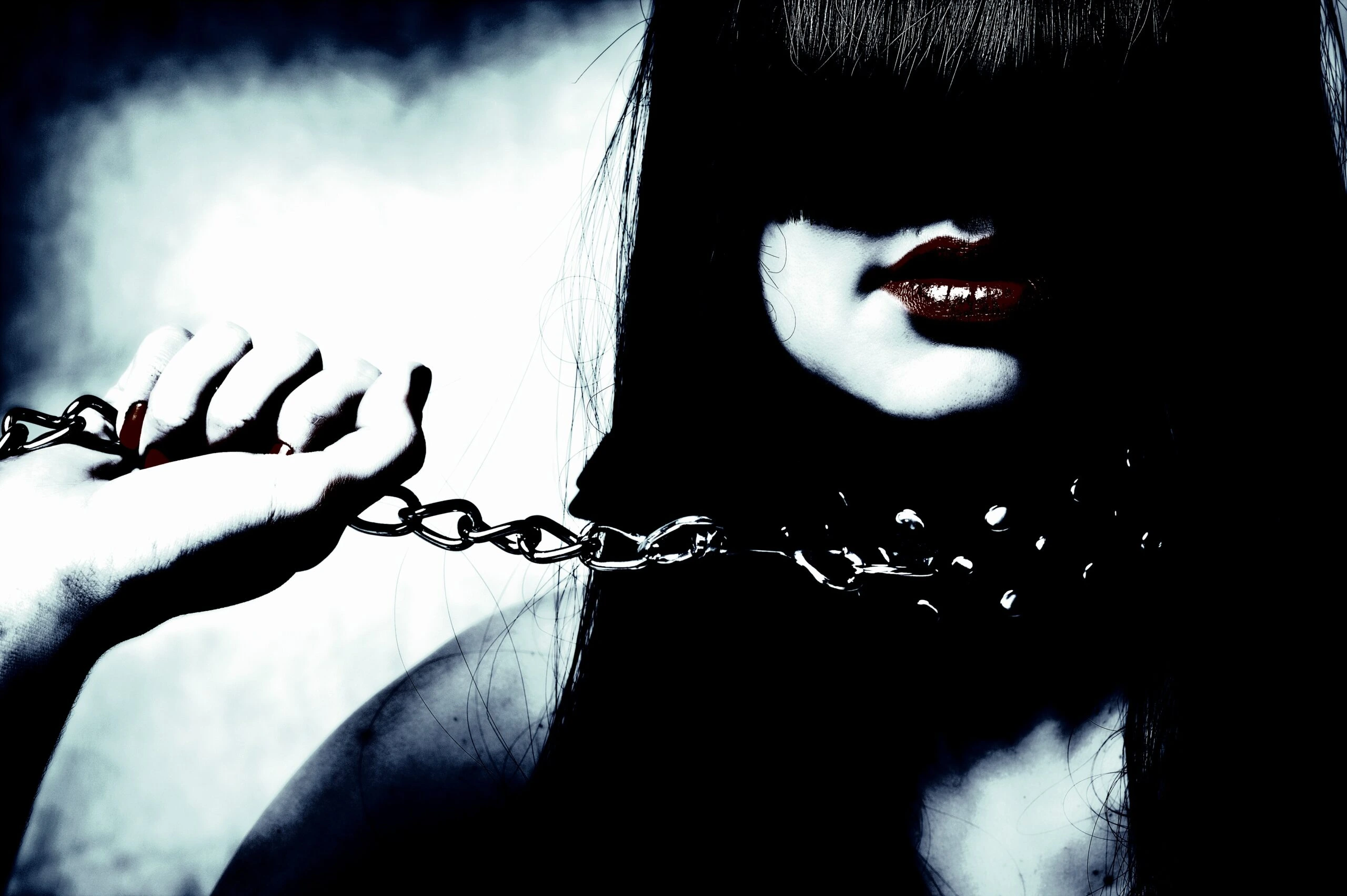 Woman in a stark, dramatic pose with hands bound by chains, reflecting the psychological dynamics of dominance and submission.