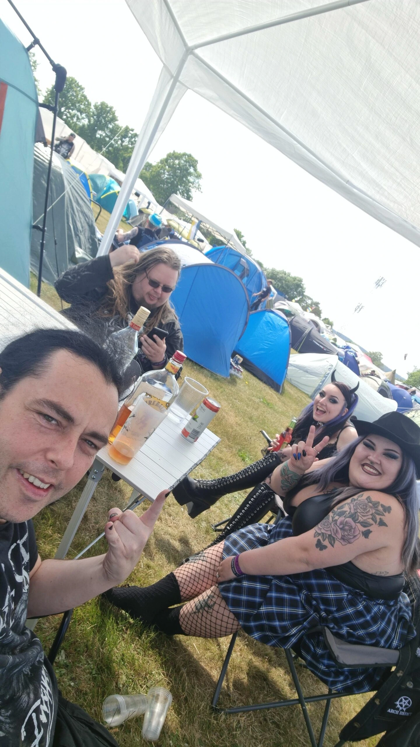 Group of friends smiling and posing with drinks at Sweden Rock Festival 2024 campsite