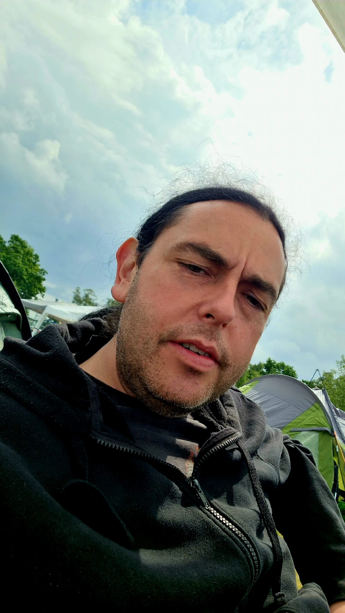 Man relaxing at the campsite with tents and cloudy sky in the background at Sweden Rock Festival 2024