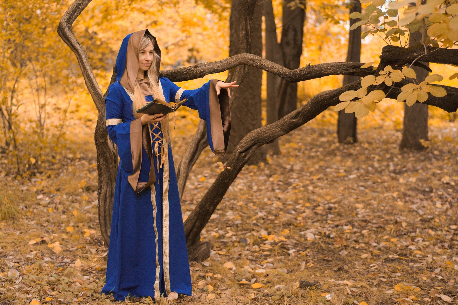 Female cosplayer dressed as a fantasy warrior with white hair, holding two green glowing swords.