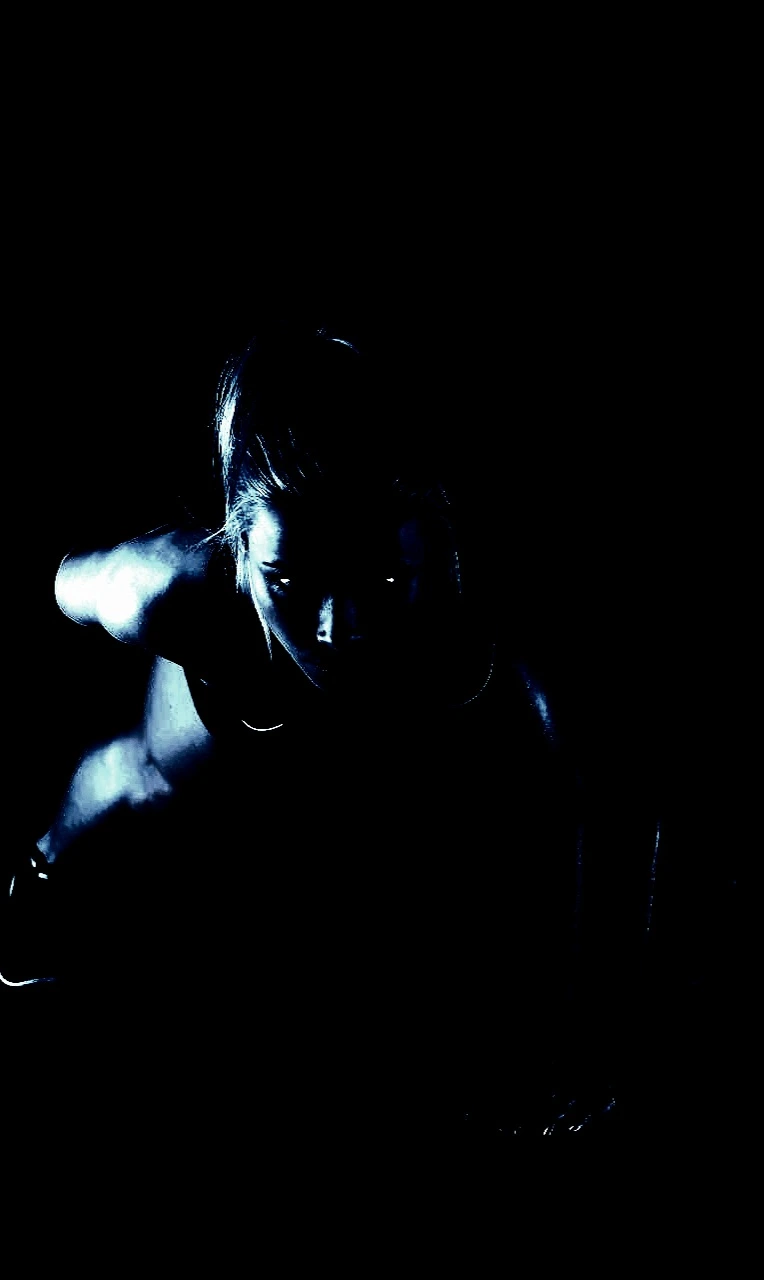 Silhouette of a woman stretching in a dimly lit room, representing Heavy Metal Yoga strength