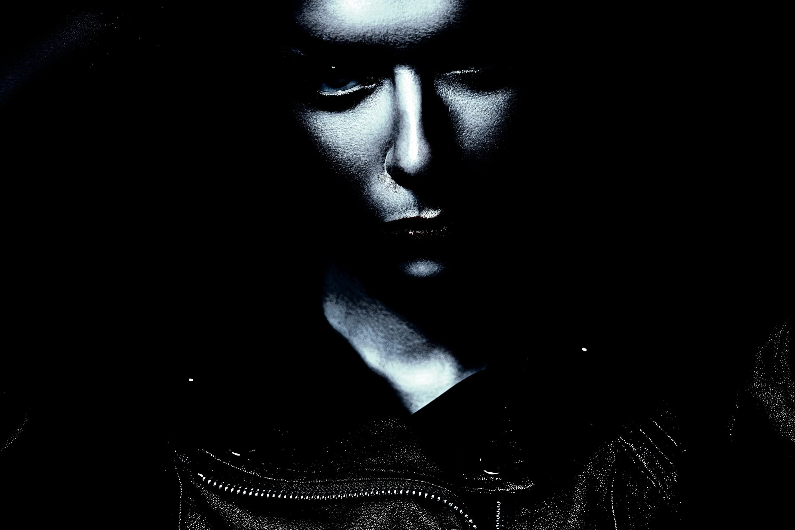 Victorian Gothic blouses: A gothic woman with a piercing gaze, her face partially obscured by shadows, wearing a black leather jacket.