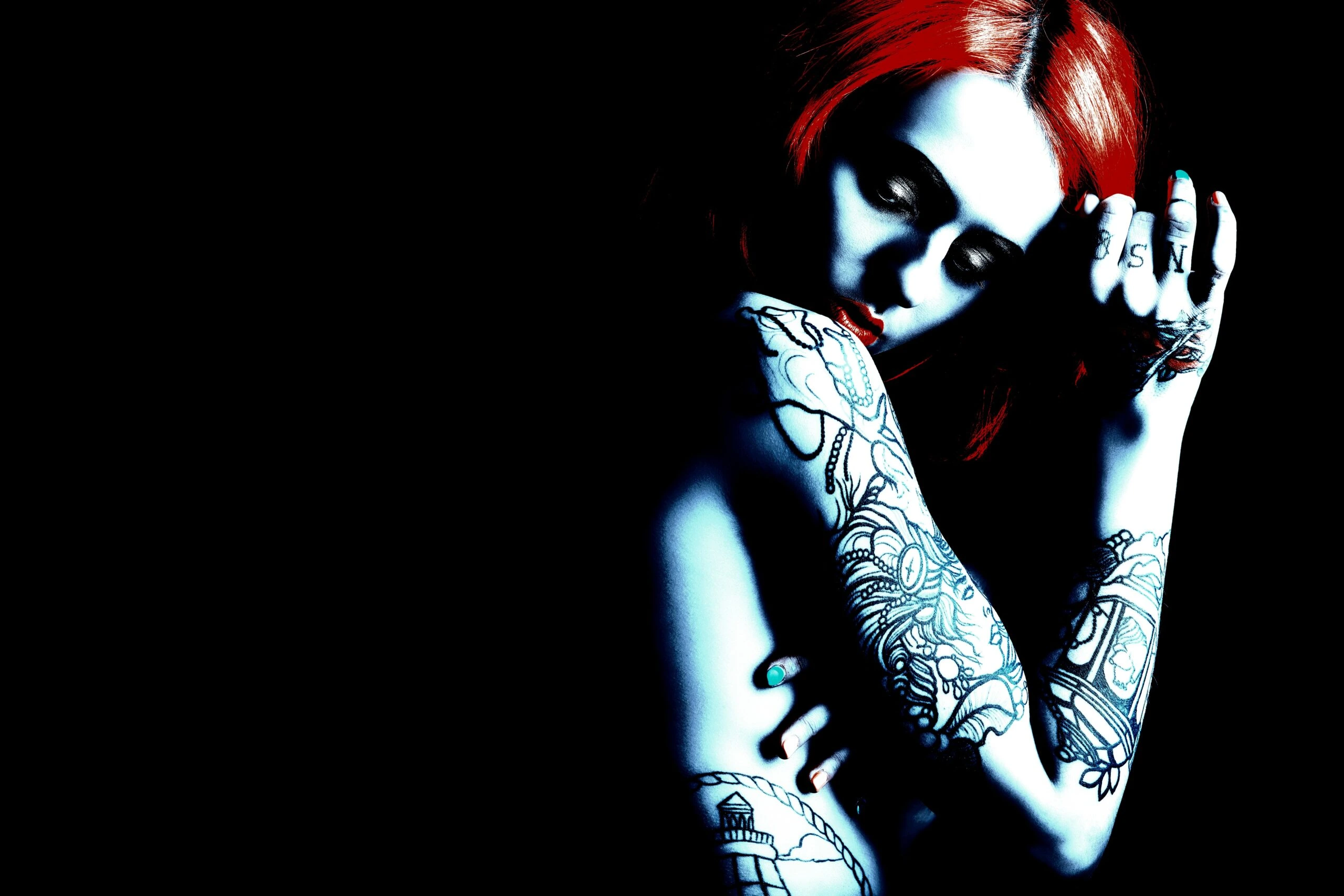 Tattooed lady in an alternative subculture with striking red hair and elaborate arm tattoos.