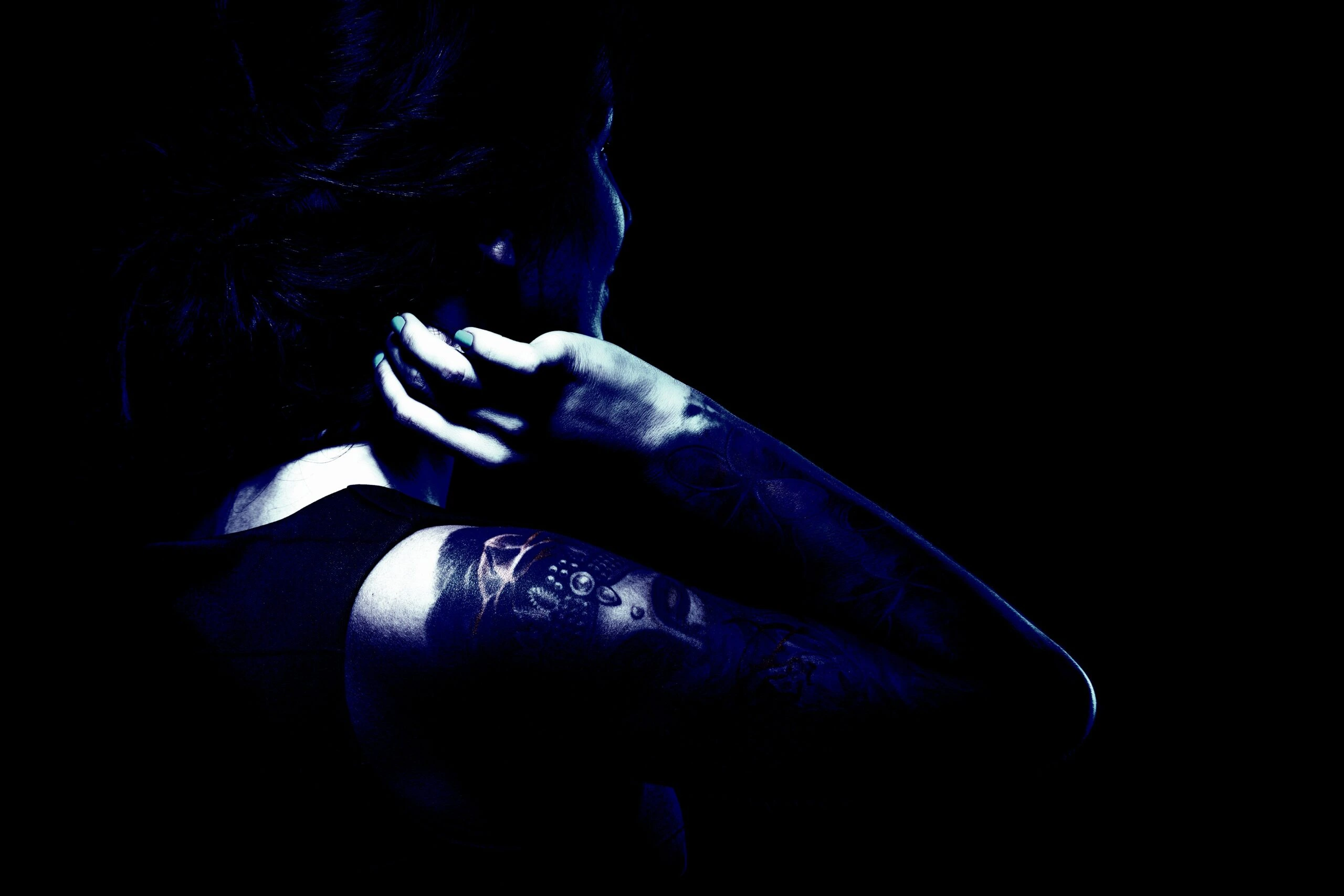 Tattooed lady in an alternative subculture seen from the back with detailed arm tattoos.