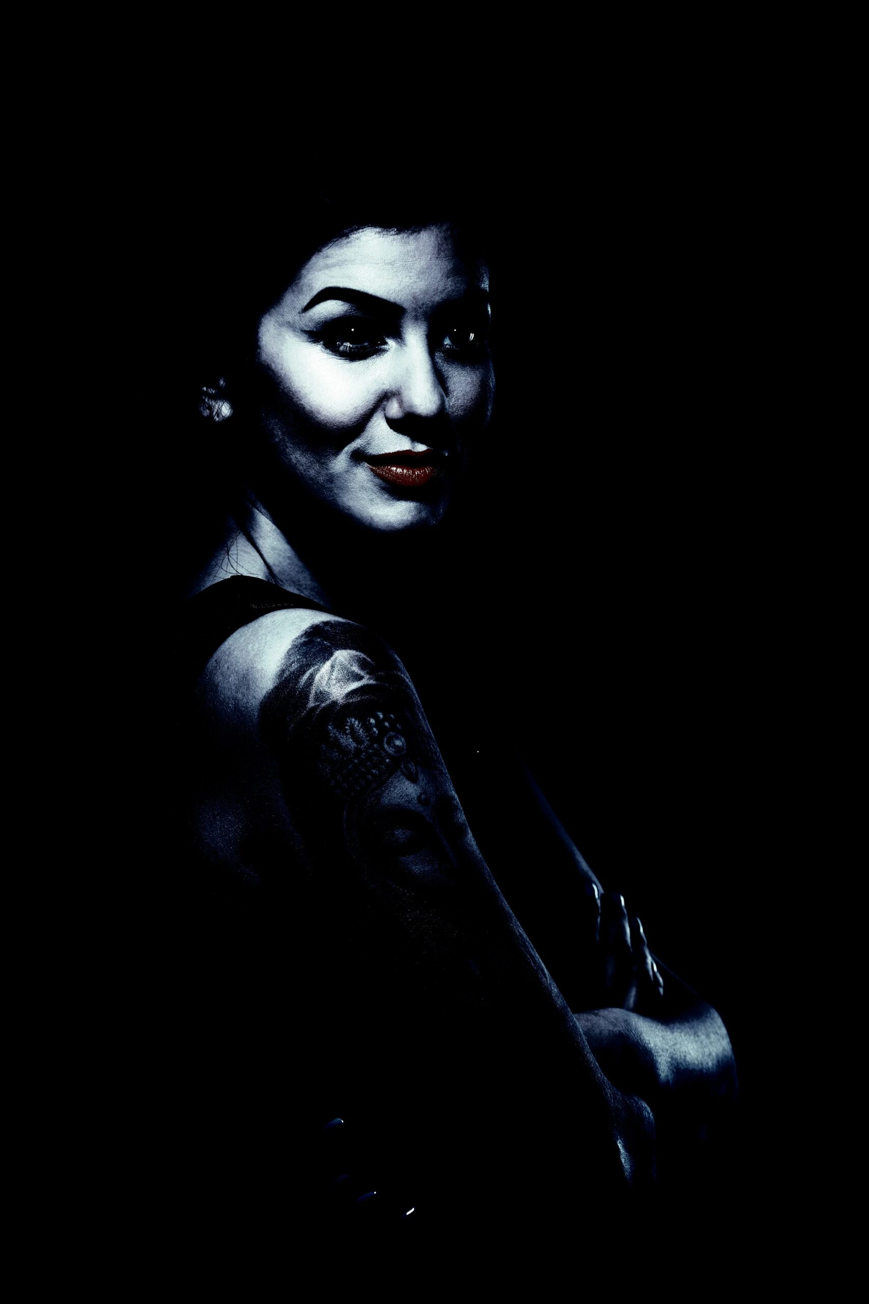 Tattooed lady in an alternative subculture posing with a confident smile and arm tattoos.