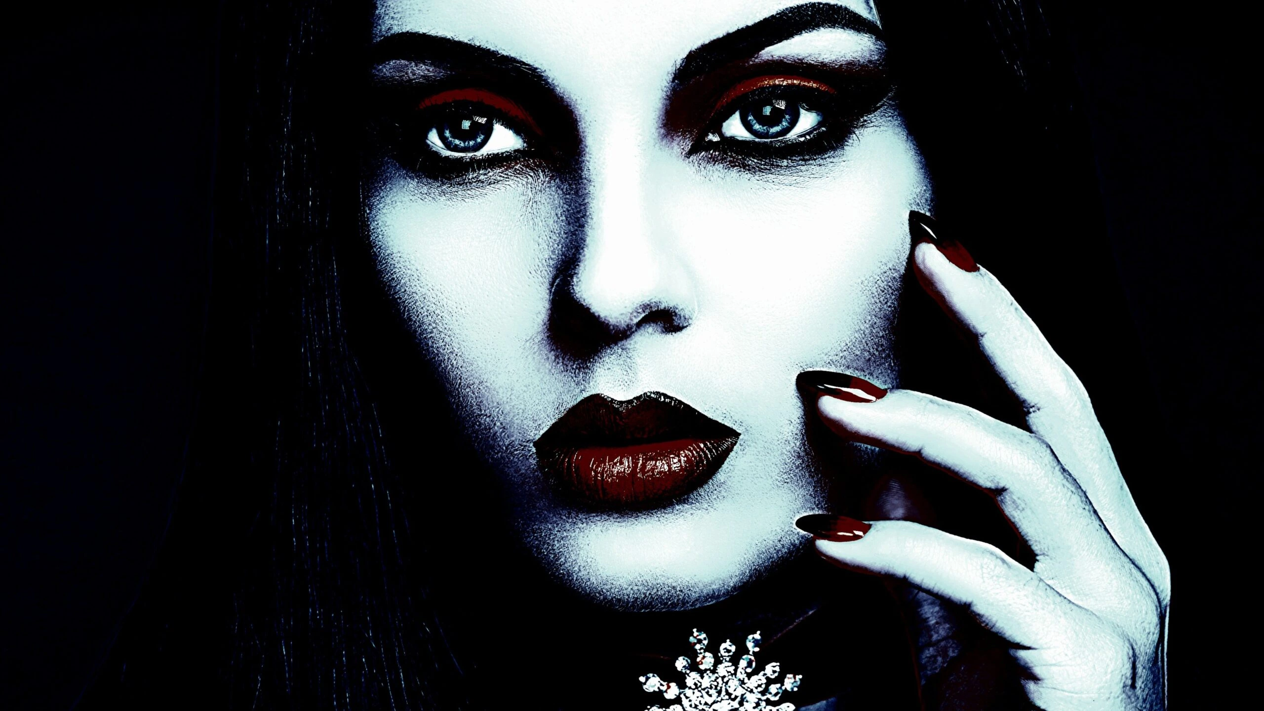 Gothic jewelry featuring an intricate snowflake gem necklace on a woman with striking makeup and dark red nails.