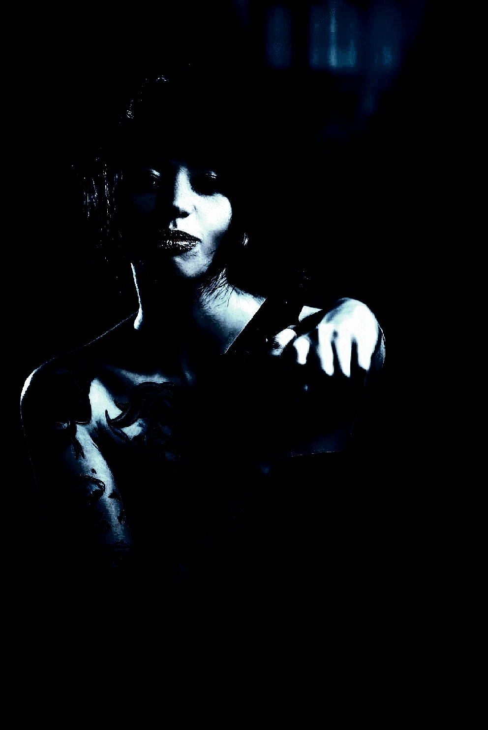 Beautiful tattooed girl in an alternative subculture wearing a black dress, pointing a gun to the camera with attitude.