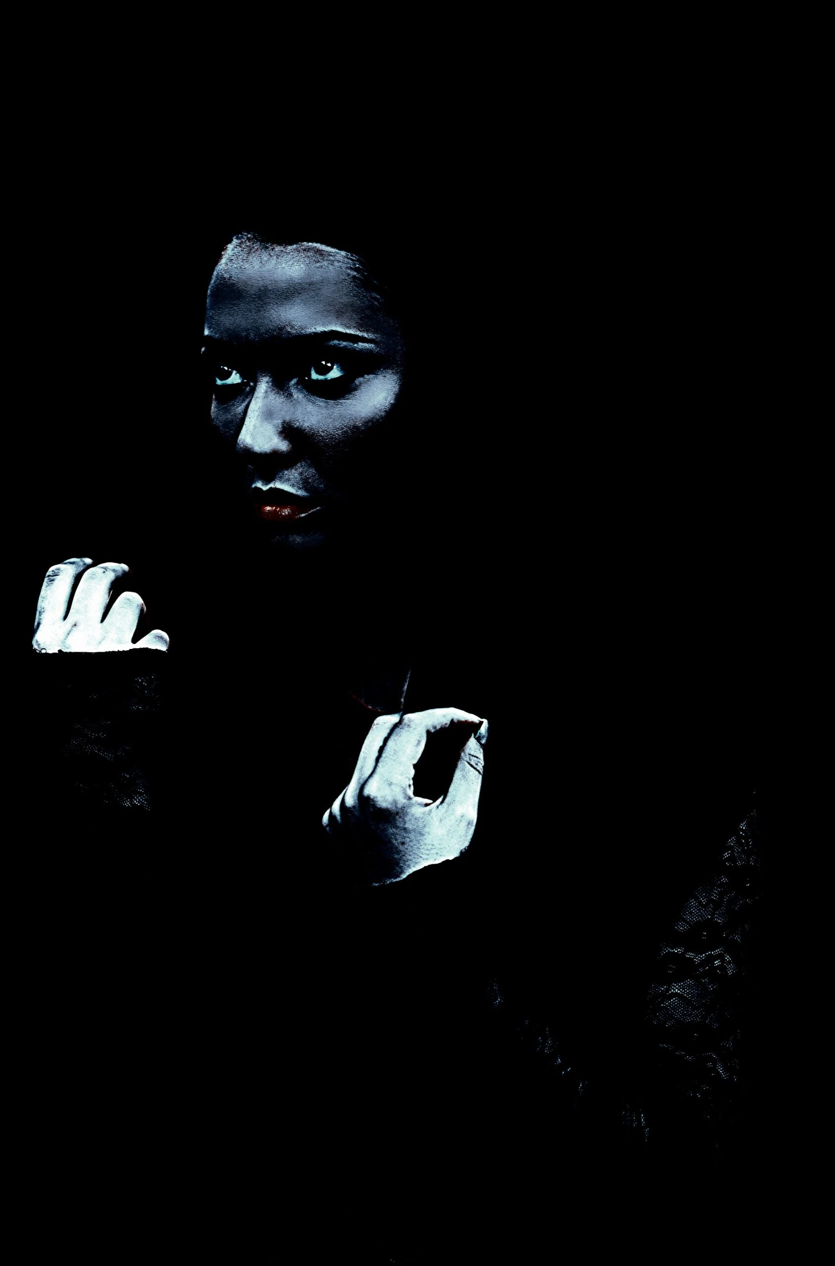 Close-up of a gothic woman in darkness, showcasing intense eyes and a mysterious aura.