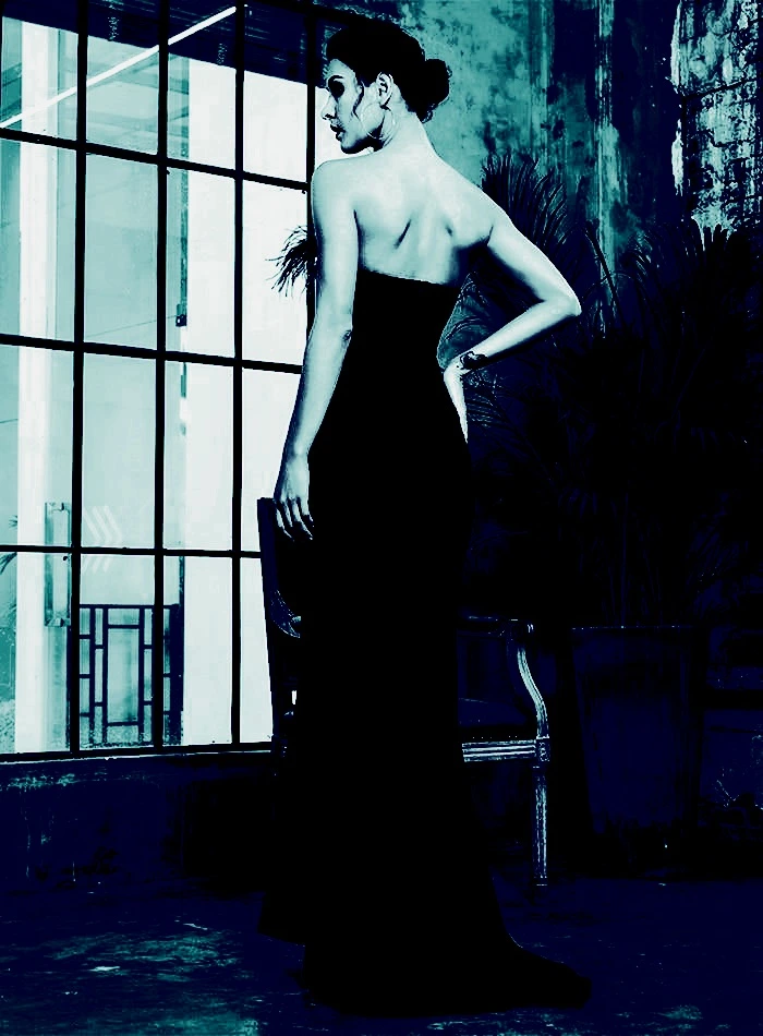 Back view of a woman in a strapless gothic maxi dress, standing in an industrial room