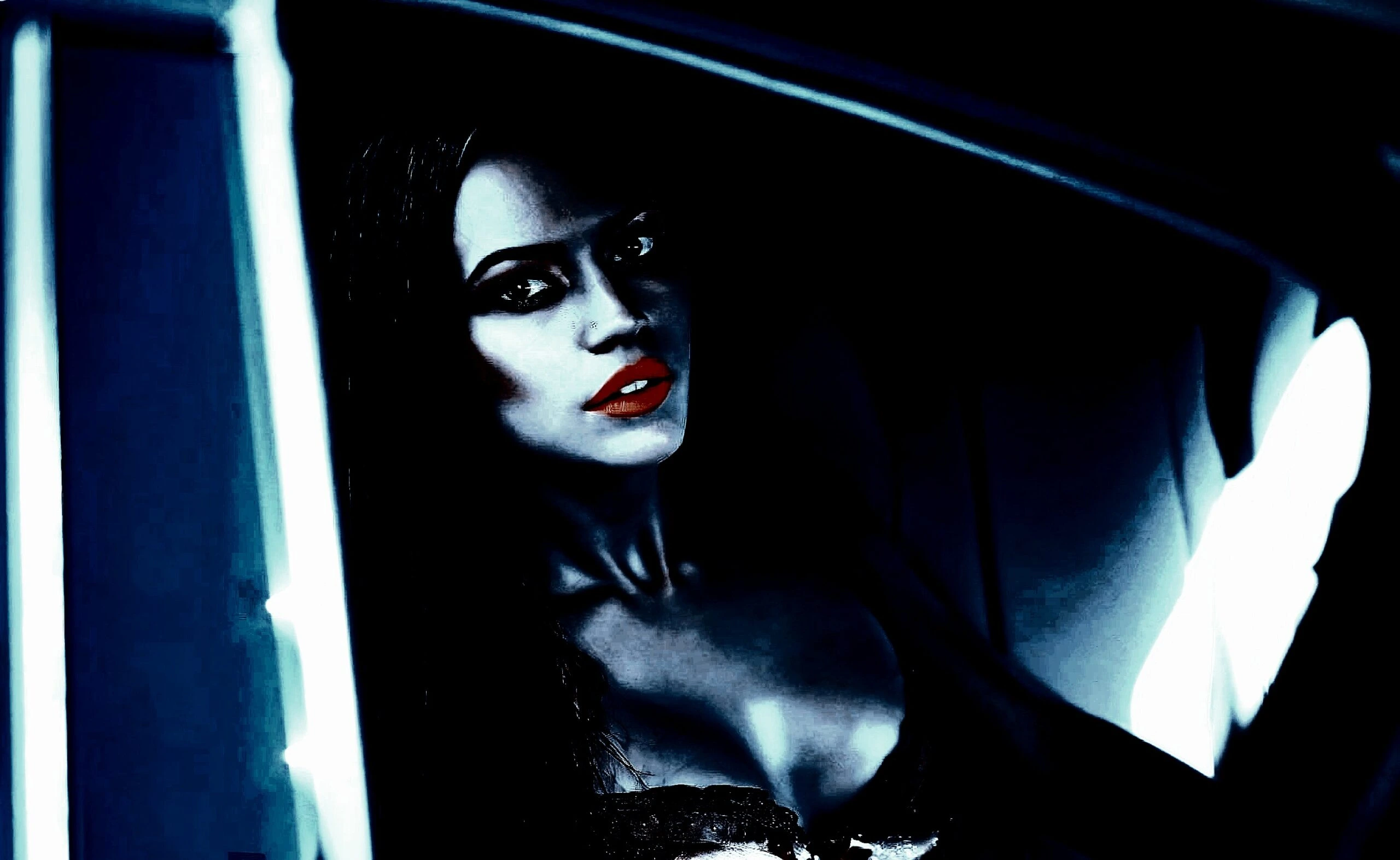 Moody, dark image of a woman with red lips sitting in a car, highlighted by dim light. 