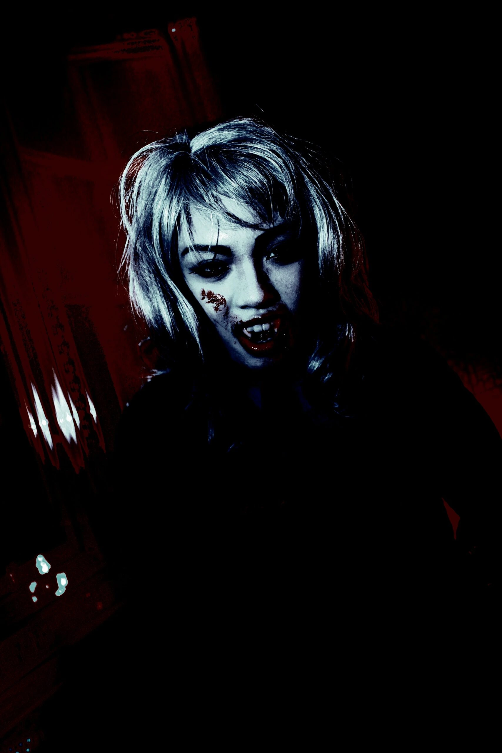 Woman with blood on her lips and fangs, wearing a dark outfit in a vampire goth velvet attire style.