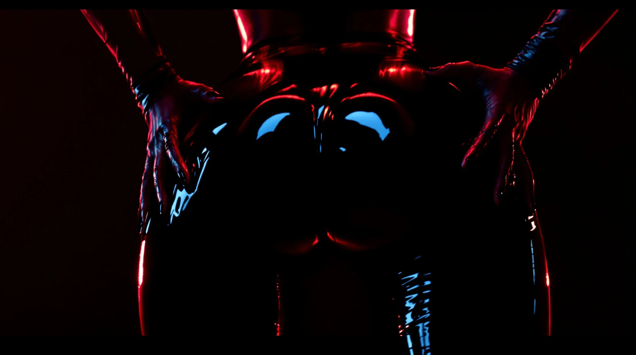 Gloved hands gripping glossy latex-clad buttocks under red and blue lights, curves reflecting high shine.