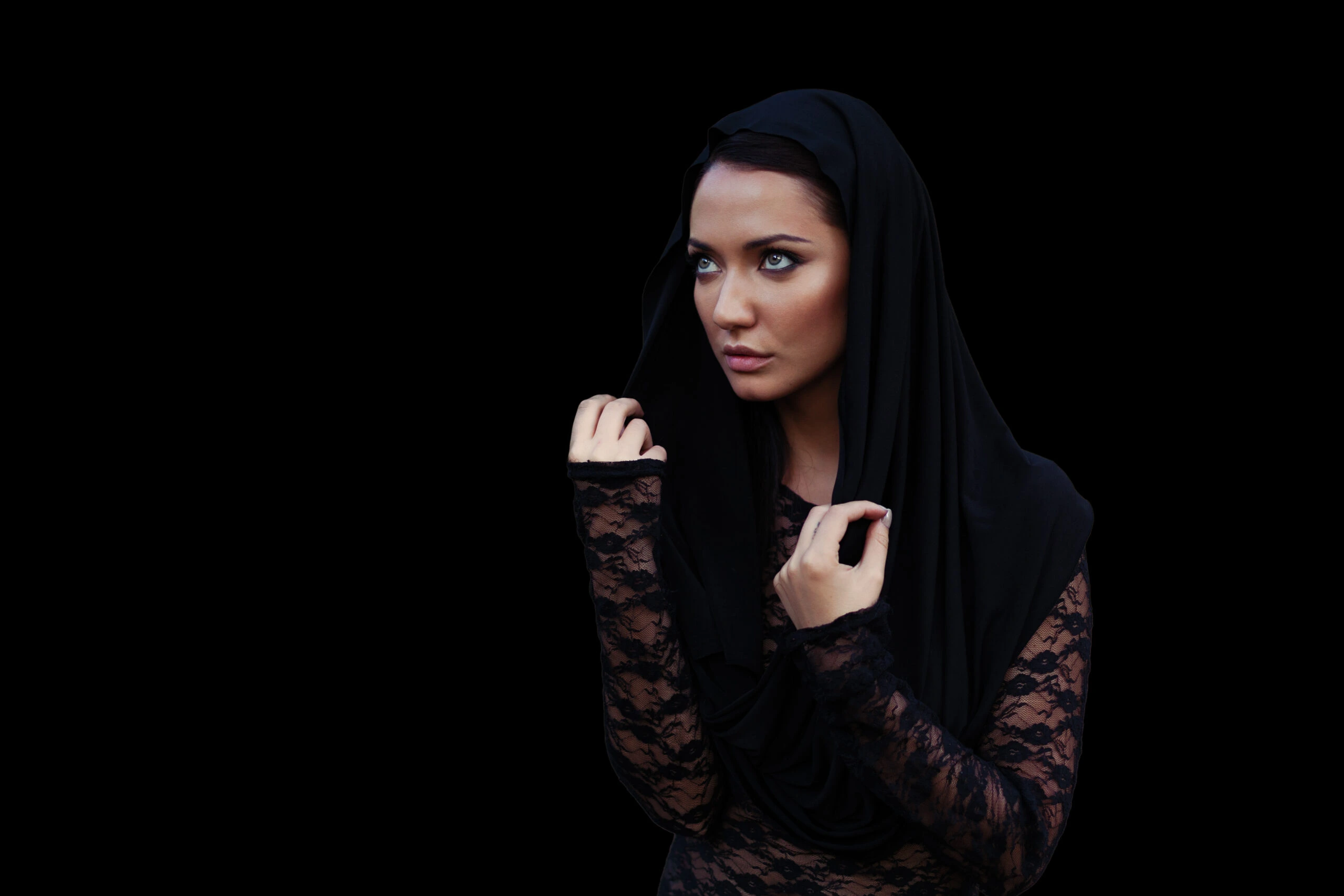 Woman in a black lace Gothic shirt with a hood, looking thoughtfully into the distance.