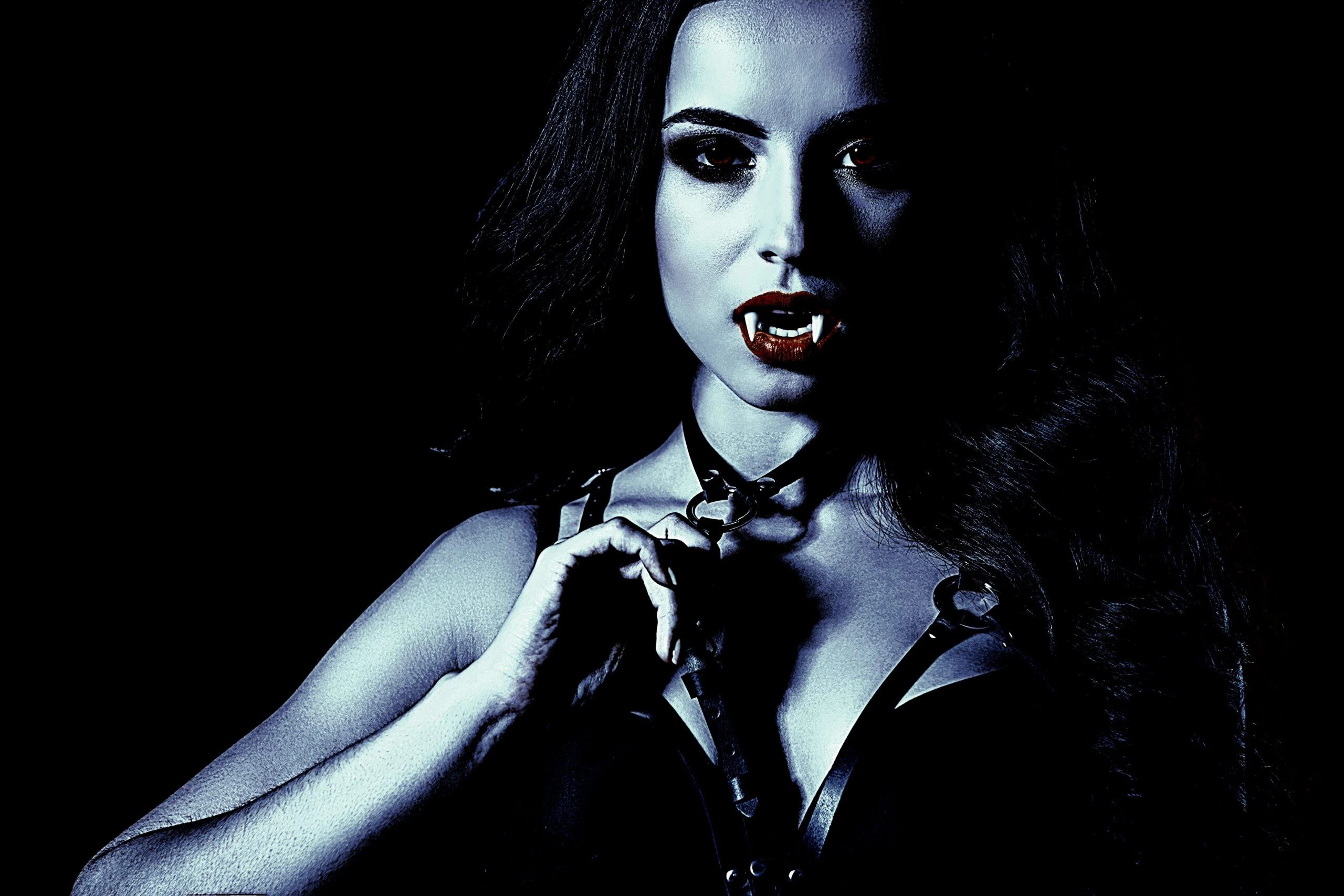 Woman with fangs wearing a black corset and gothic makeup, embodying vampire goth velvet attire.