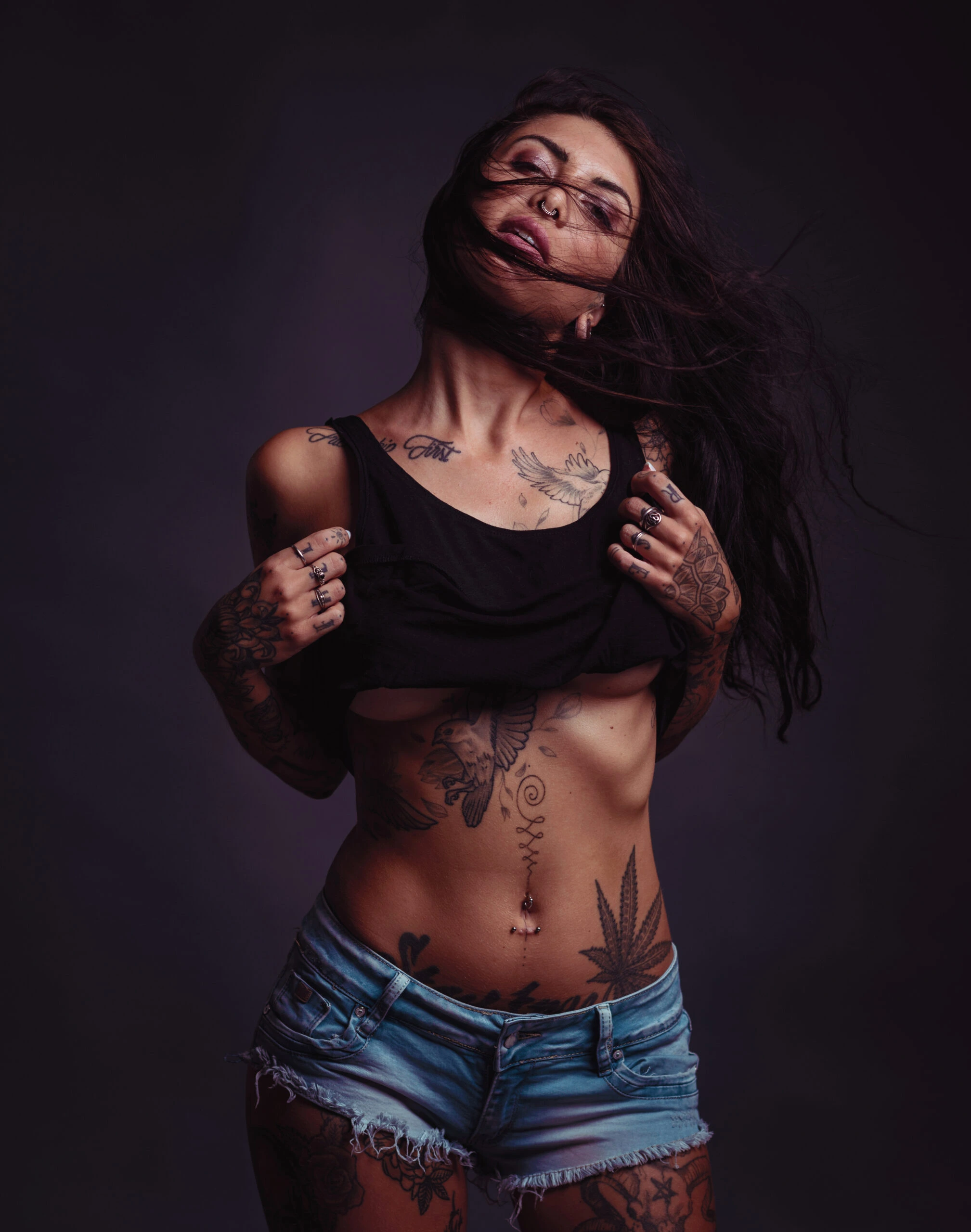 Tattooed woman in a crop top and denim shorts, embracing an alternative, rebellious style.