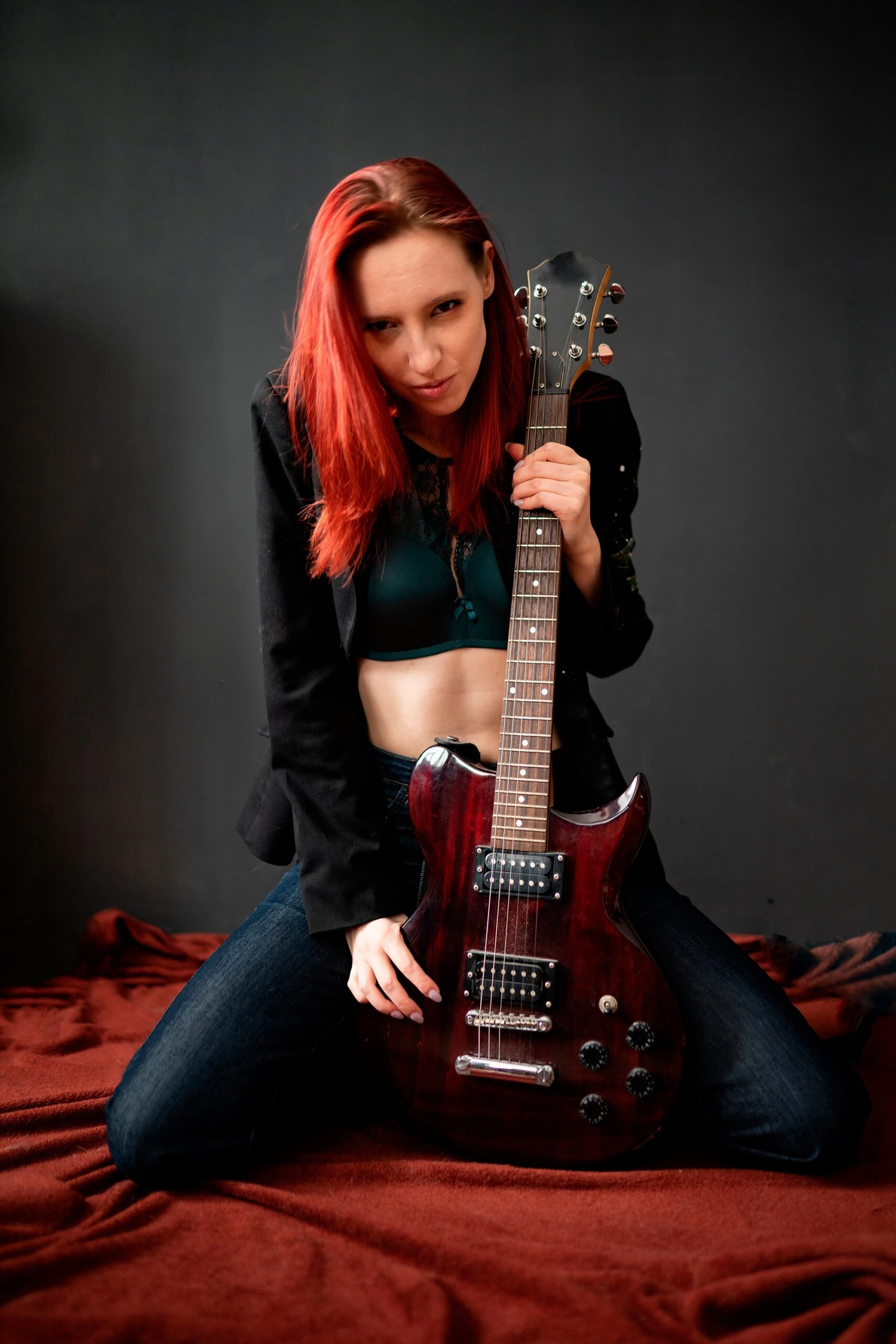 Red-haired woman with a guitar, dressed in dark attire, showcasing a rock-inspired gothic look.