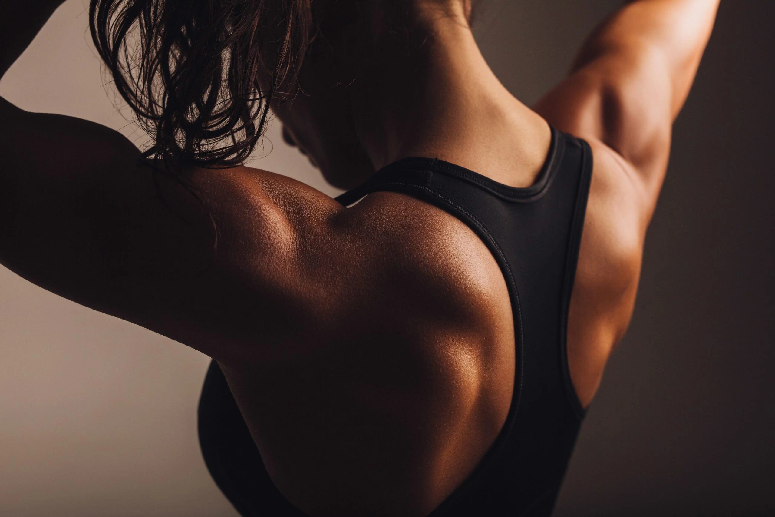 Close-up of a woman's muscular shoulders and back in a gym