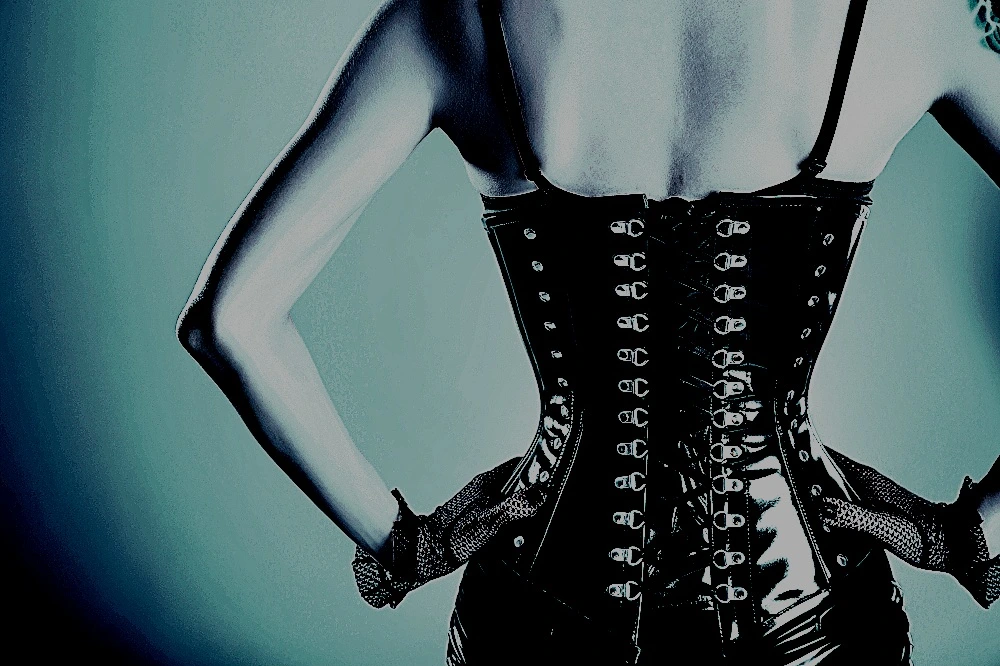 How to tight lace a corset: Close-up of a black leather corset being laced up, showcasing the intricate detailing and tight lacing process.