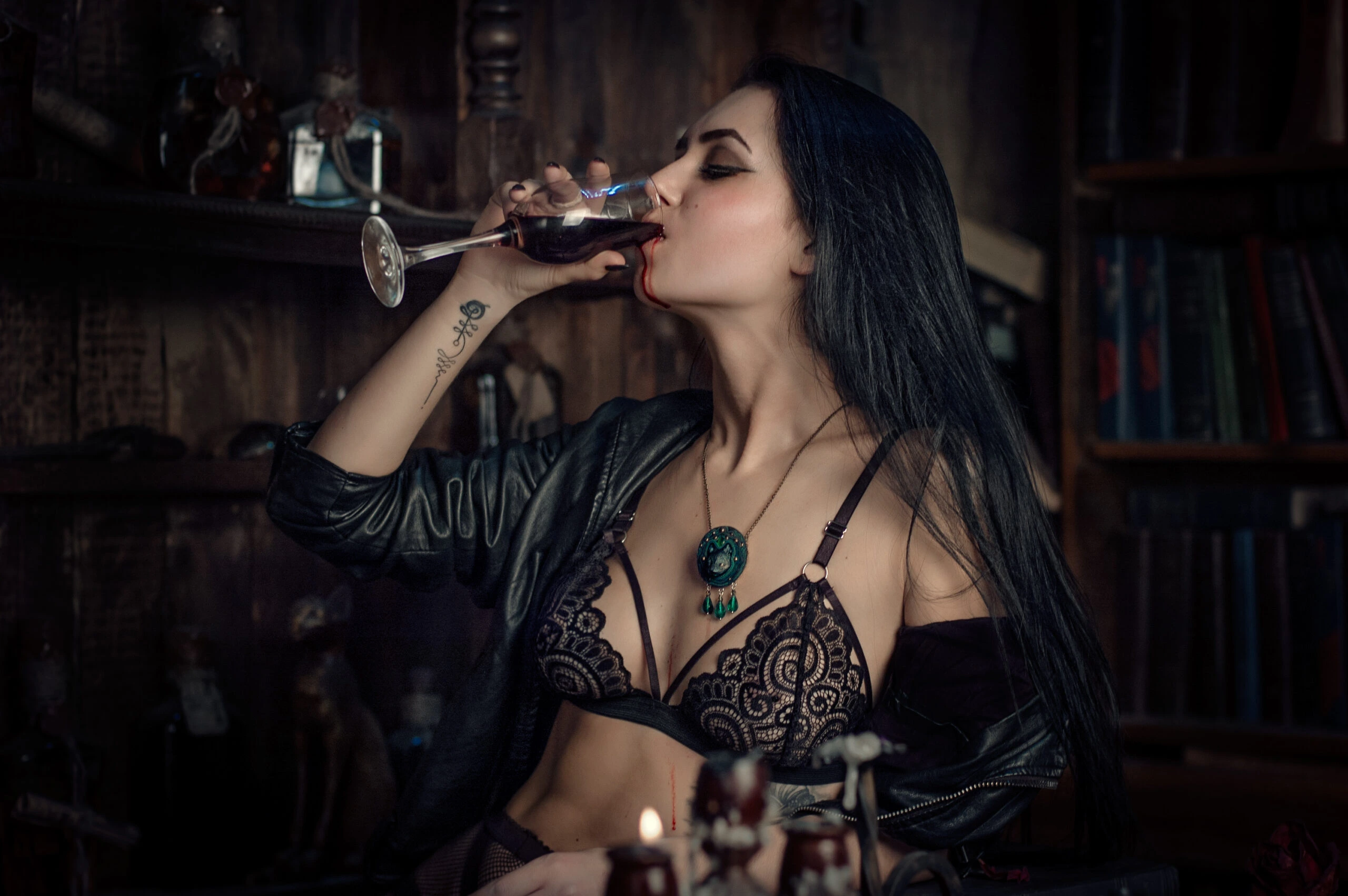 A woman in black lace lingerie drinking from a wine glass filled with blood, exuding a seductive, modern vampire vibe.