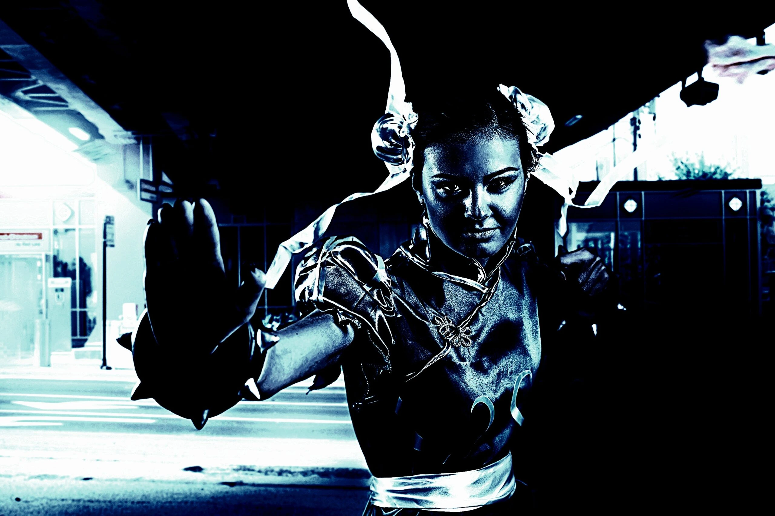 Metalhead cosplayer in a combat-ready pose, dressed as a character with twin buns and ribbons in a dark urban setting.