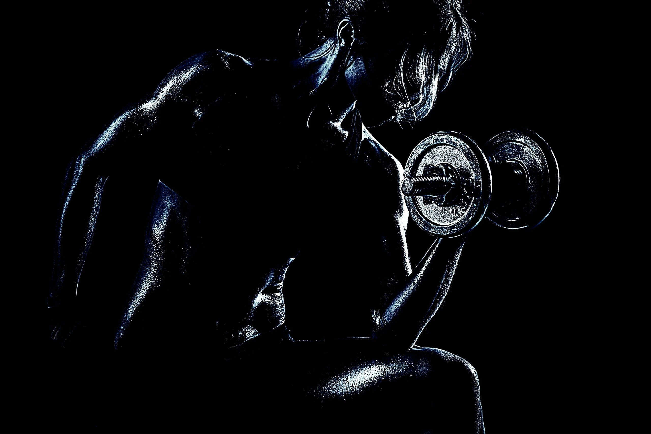 Fit woman holding dumbbells and flexing her muscles in a high-contrast fitness shot