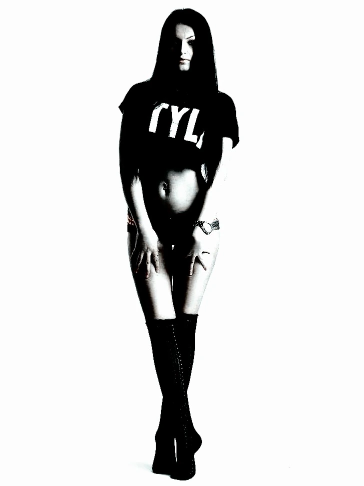 Woman in a t-shirt and high boots, posing confidently with a white background.