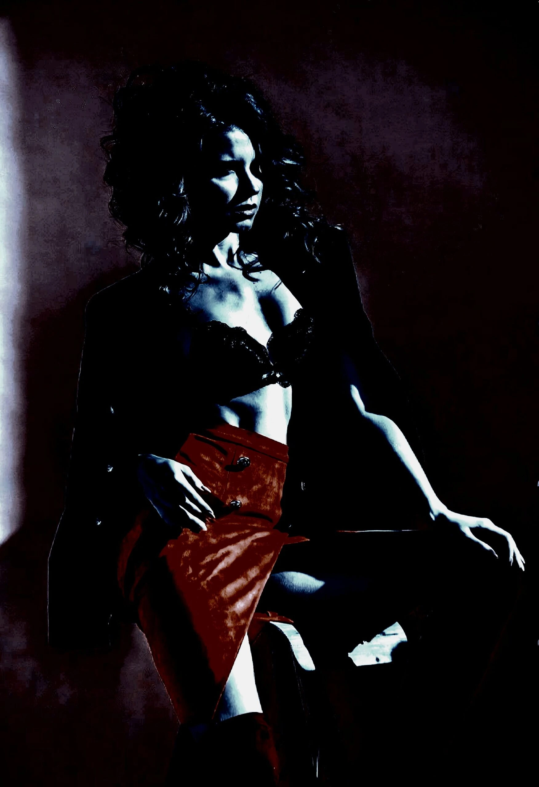 Woman wearing glasses and sitting provocatively on a desk in an office setting. 