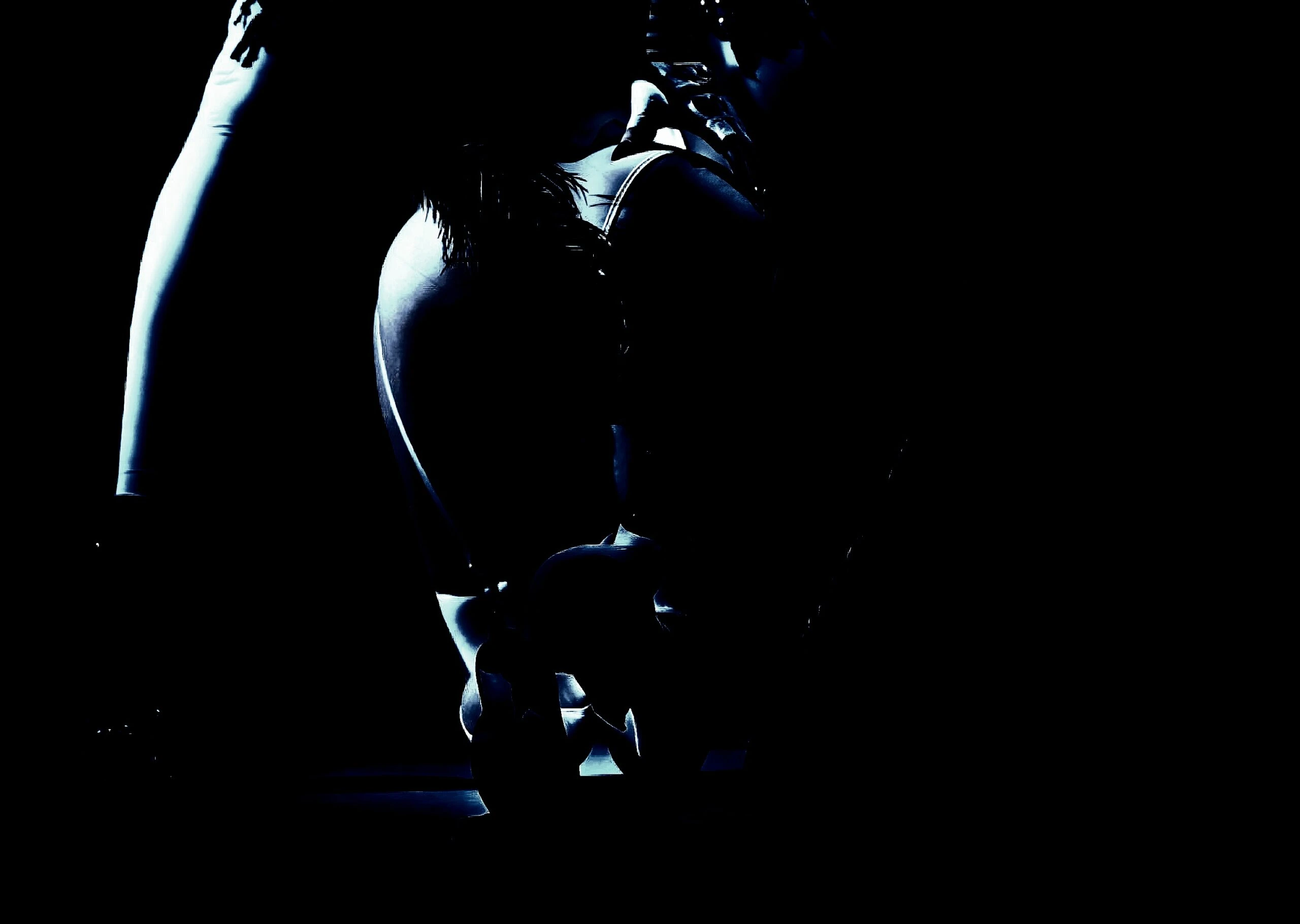 Silhouette of a person kneeling in a dark environment with focused light highlighting their curves.