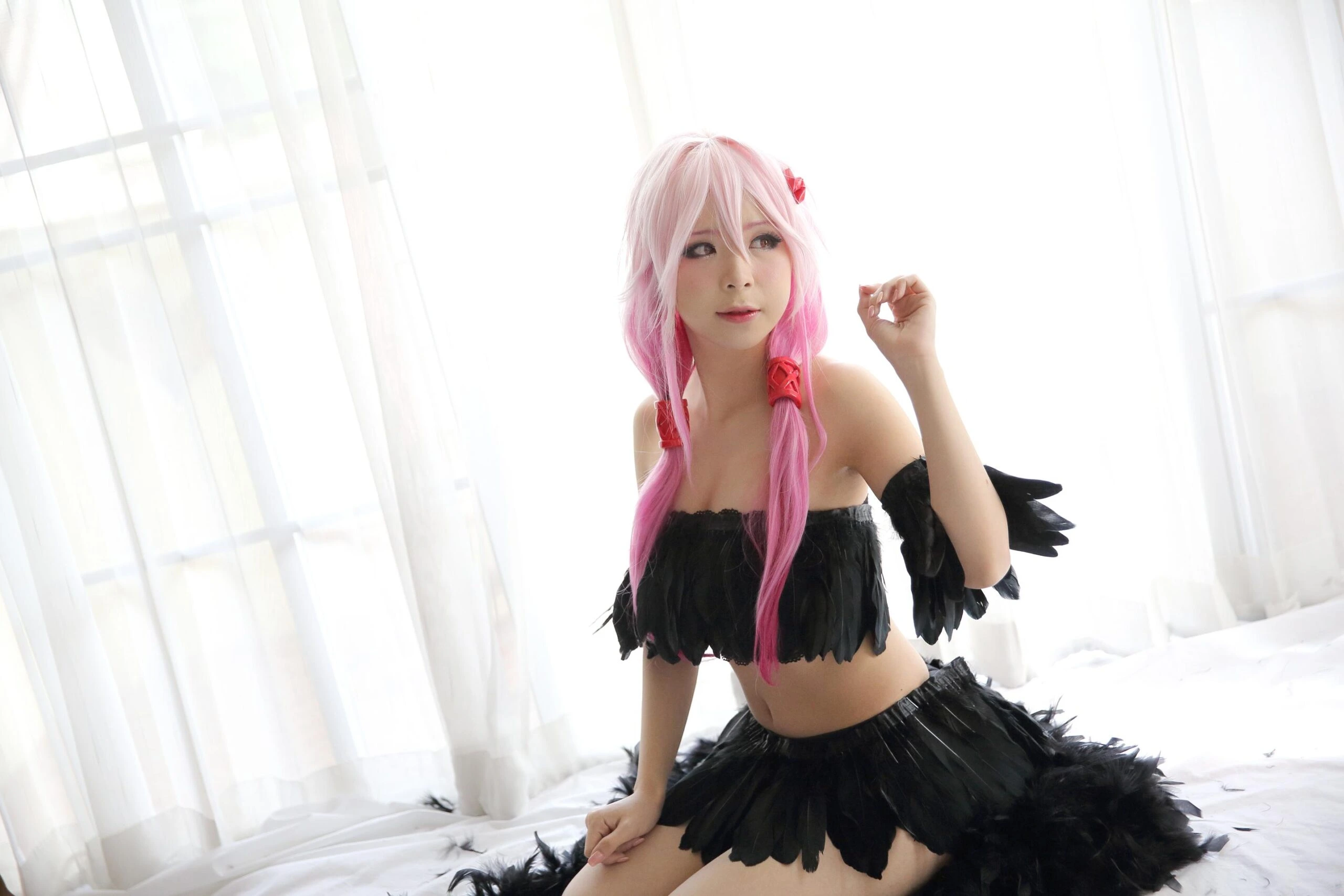 A cosplayer with pink hair styled in twin braids, wearing a black feathered outfit, sitting gracefully in a bright room with white curtains, creating a soft and whimsical scene.